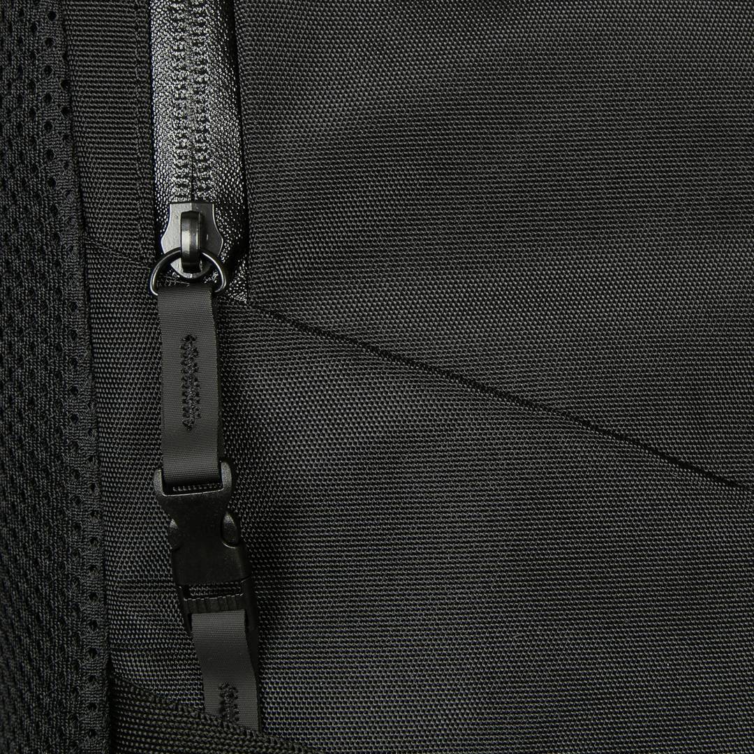 Zbliżenie czarnego zamka błyskawicznego na torbie, ukazujące szczegóły faktury i szwów materiału.