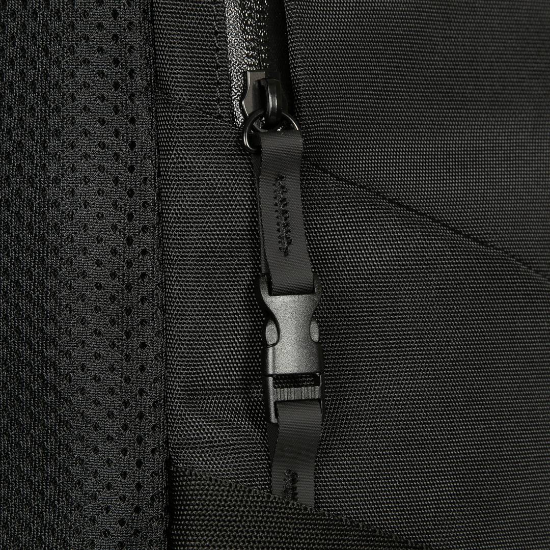 Zbliżenie czarnego plecaka z zamkiem błyskawicznym. Wyraźna tekstura i szczegół zamka są dobrze widoczne.