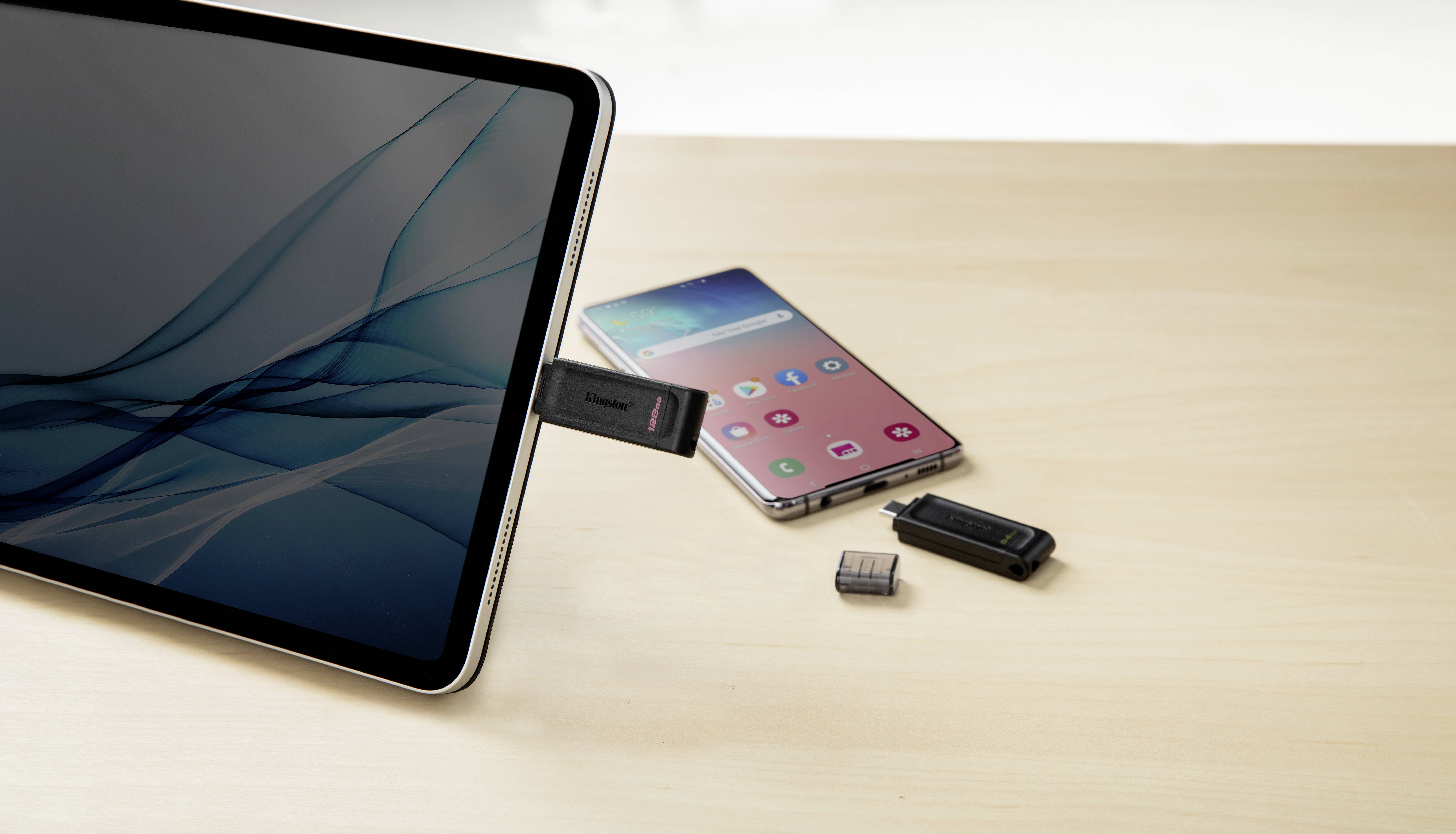 Tablet podłączony do pendrive'a, obok smartfon i nośnik pamięci na stole. Prezentacja łączności danych między urządzeniami.