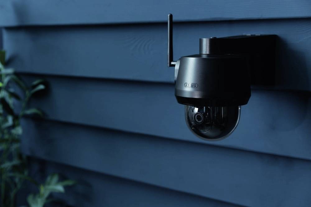 Kamera monitorująca znajduje się na niebieskiej ścianie i kontroluje otoczenie.