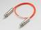 Pomarańczowy kabel światłowodowy z dwoma srebrnymi złączami na końcach, na szarym tle.