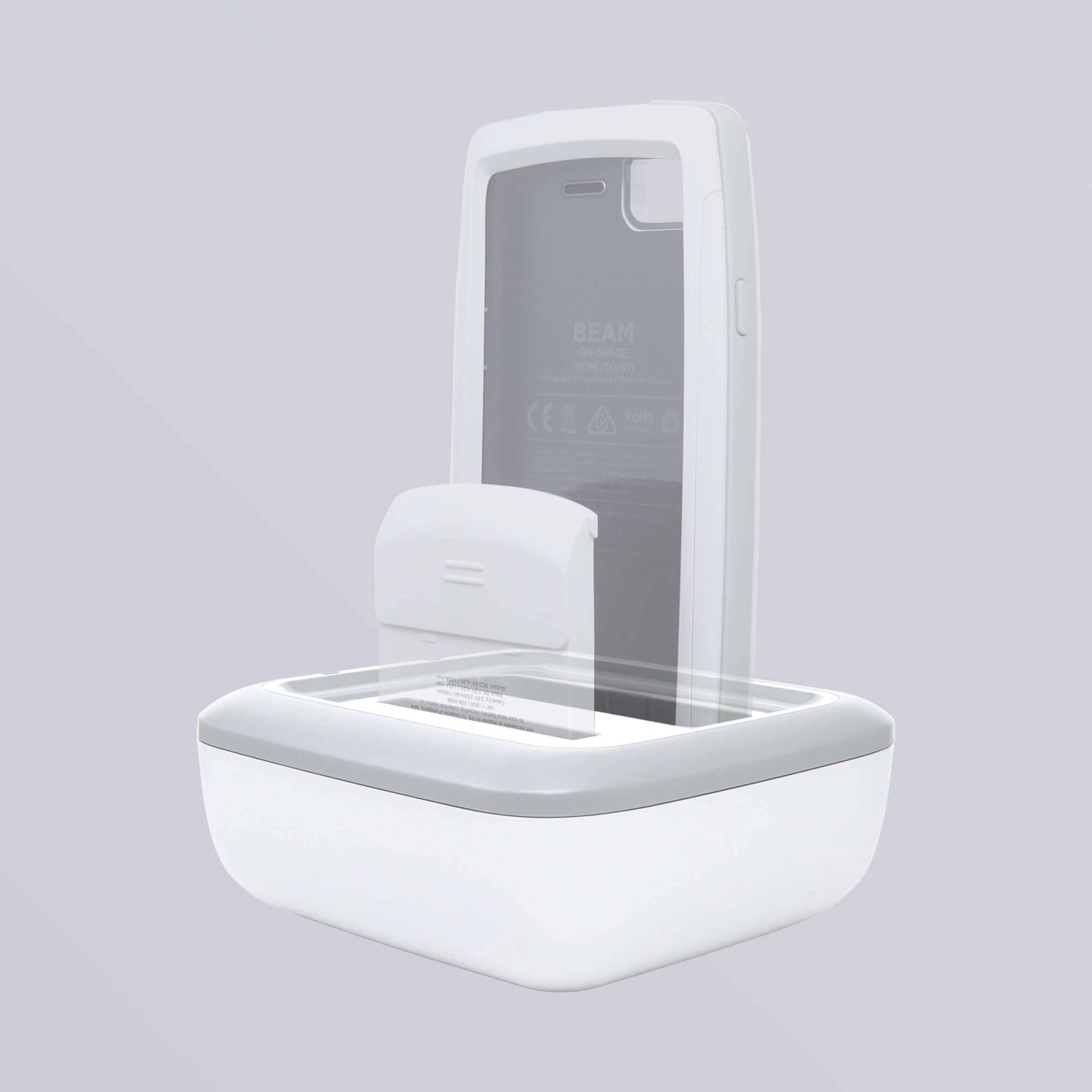 Biały, kwadratowy pojemnik do dezynfekcji smartfonów z przezroczystą pokrywą, otwarty; wewnątrz znajduje się smartfon, tło szare.