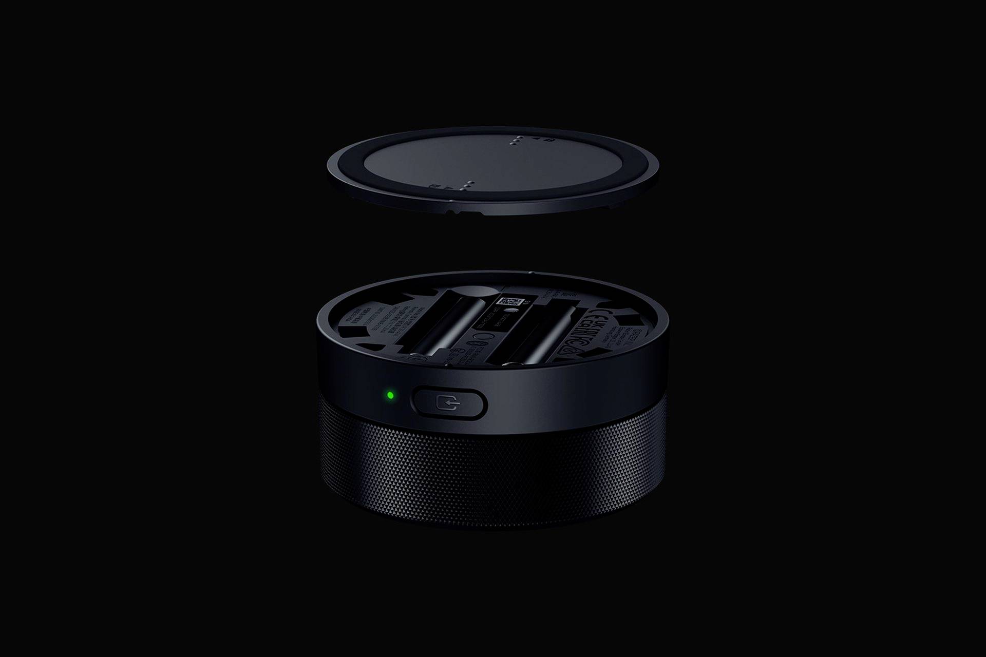 Czarny, okrągły głośnik z możliwą do zdjęcia osłoną unosi się ponad czymś. Zielone światło na przedniej części wskazuje na gotowość do pracy.