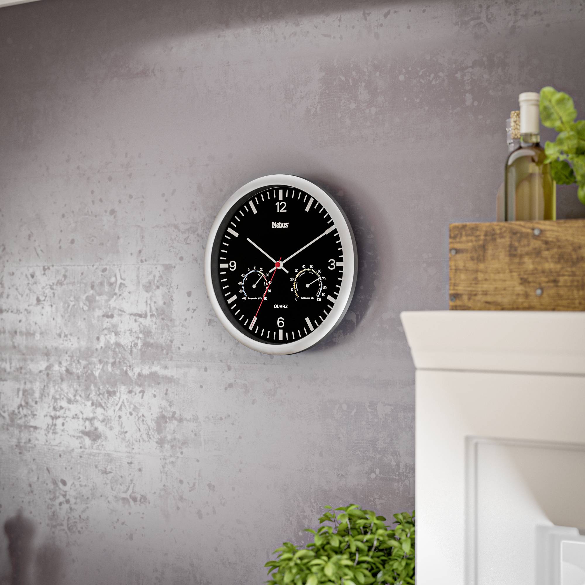 Okrągły zegar ścienny z czarną tarczą i białymi cyframi wskazuje godzinę 10:09. W lewym dolnym rogu widać roślinę.