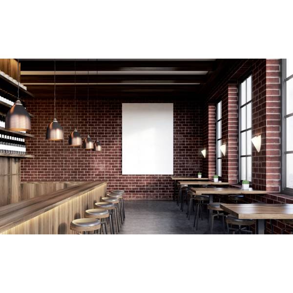 Nowoczesna kawiarnia z murowanymi ścianami, drewnianymi stołami i krzesłami. Wiszące lampy i duże okna tworzą przytulną atmosferę.