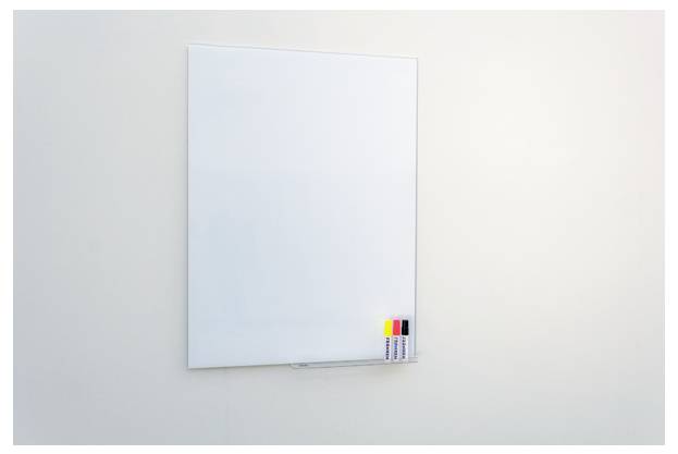 Pusta tablica whiteboard na ścianie z czterema kolorowymi markerami w dolnym prawym rogu.