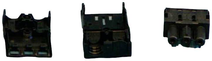 'Trzy czarne elementy elektroniczne. Z lewej: złącza, w środku: widoczne sprężyny, z prawej: trzy cylindryczne złącza.'