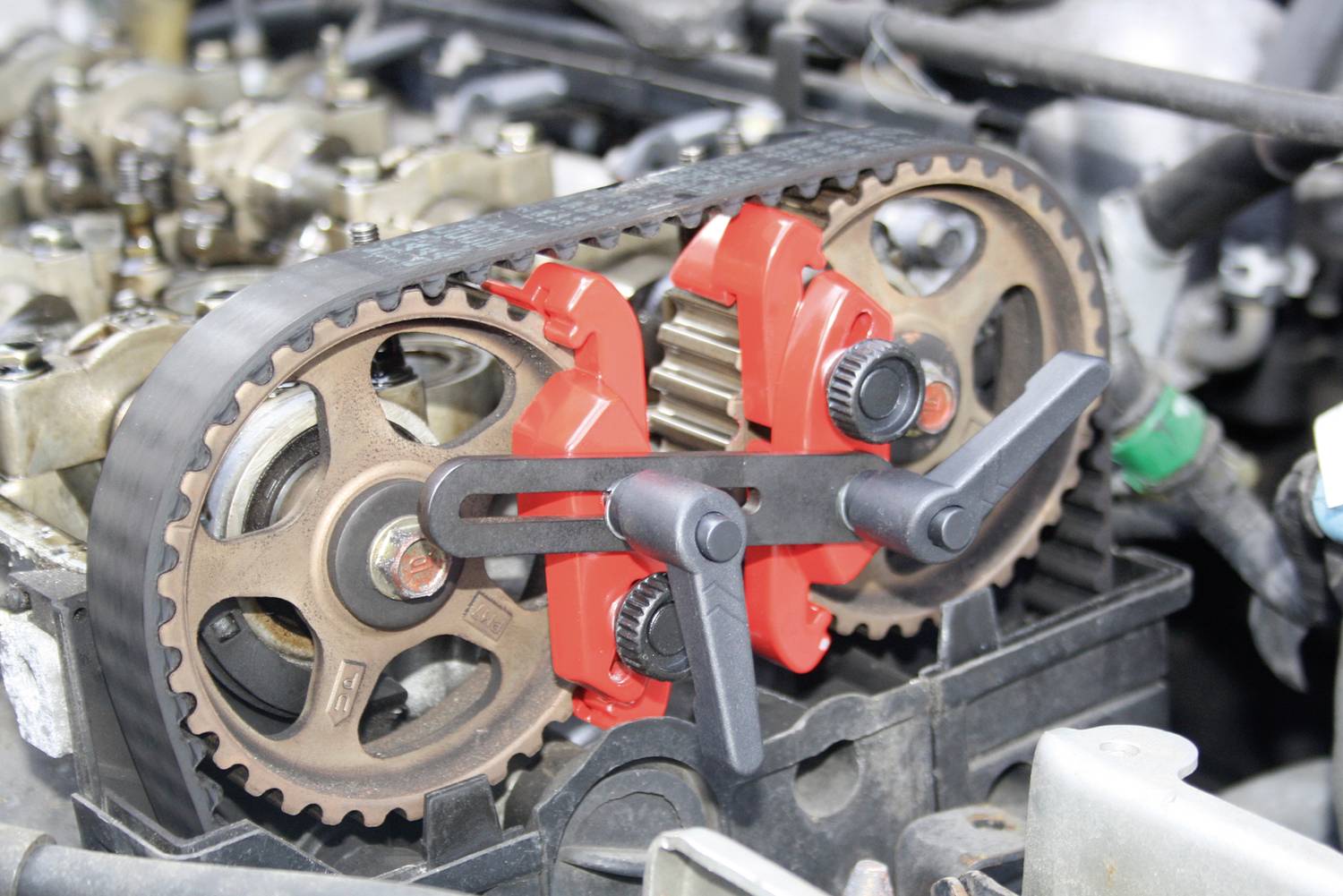 'Otwarta komora silnika z pasem rozrządu i dwoma błyszczącymi kołami wałków rozrządu w zbliżeniu, prezentująca kluczowe komponenty samochodu.'