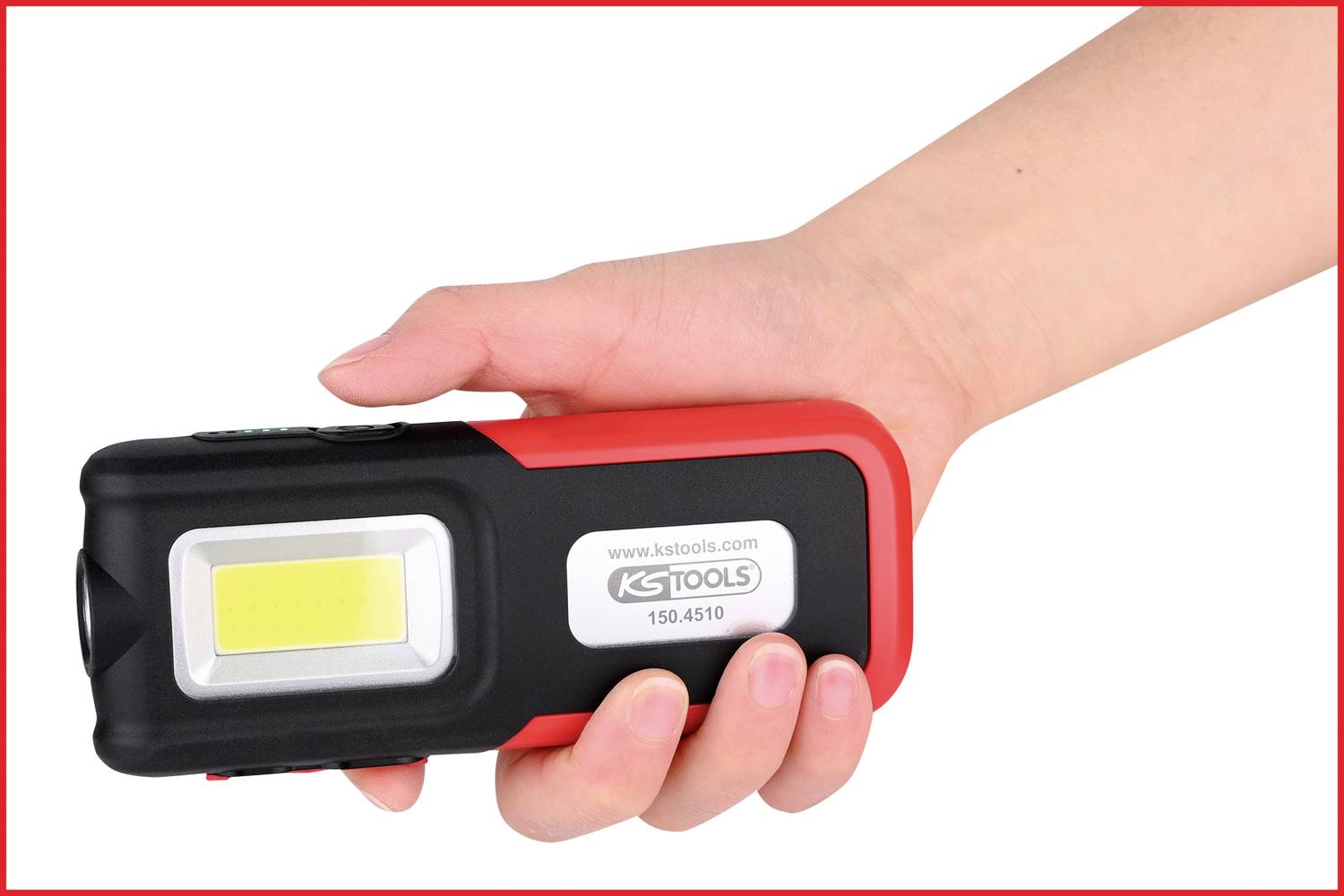 Dłoń trzyma czerwoną i czarną latarkę marki 'KS TOOLS', o numerze modelu 150.4510. Latarka posiada jasne, prostokątne światło.