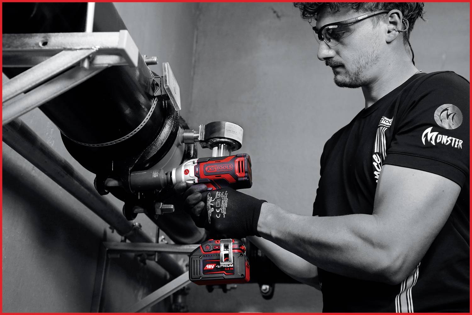 Mężczyzna w stroju roboczym szlifuje metalową rurę za pomocą czerwonego elektronarzędzia. Ma na sobie okulary ochronne i rękawice.