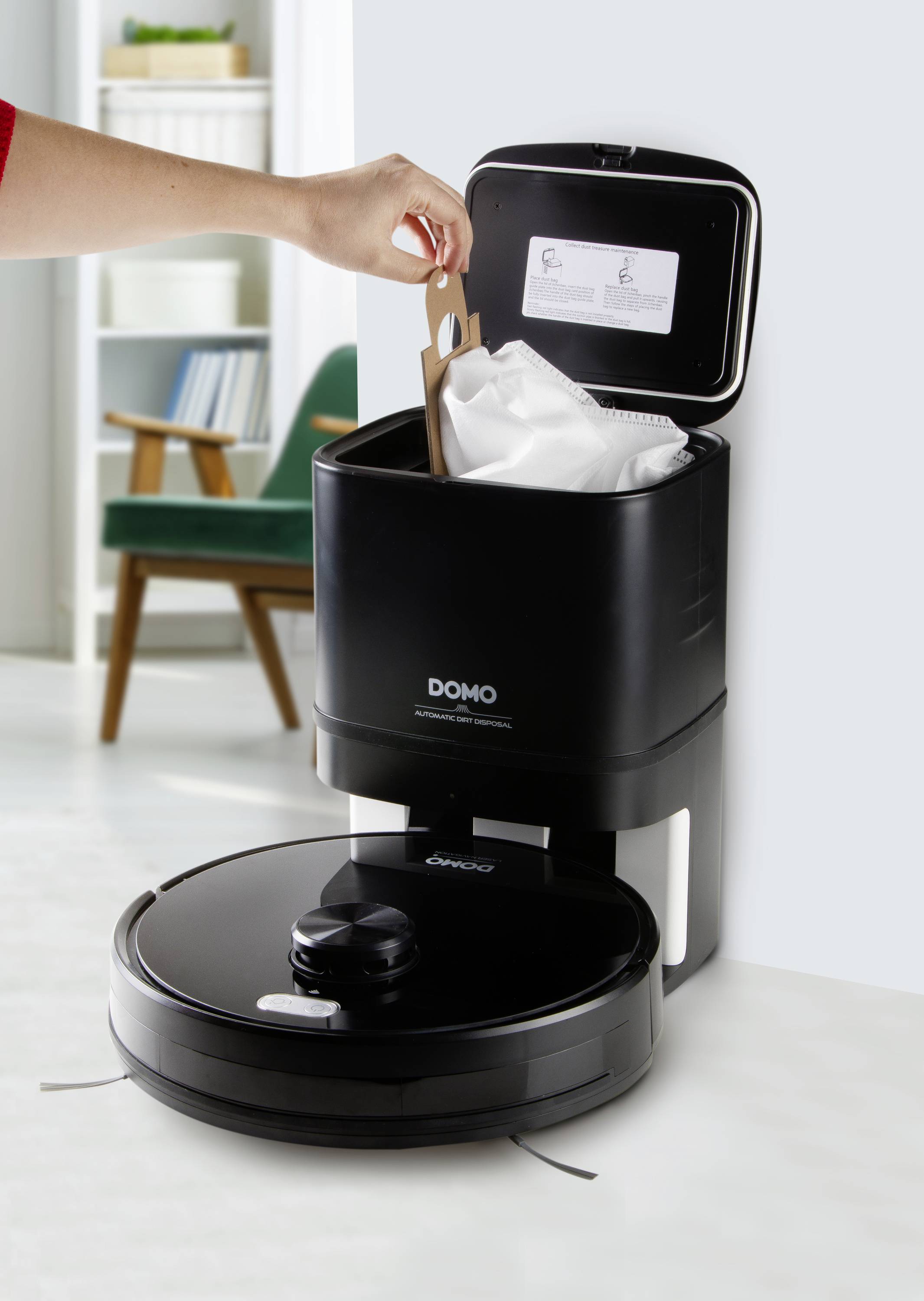 Osoba opróżnia robota sprzątającego do stacji dokującej. Robot i stacja są czarne, na tle jasnego salonu.