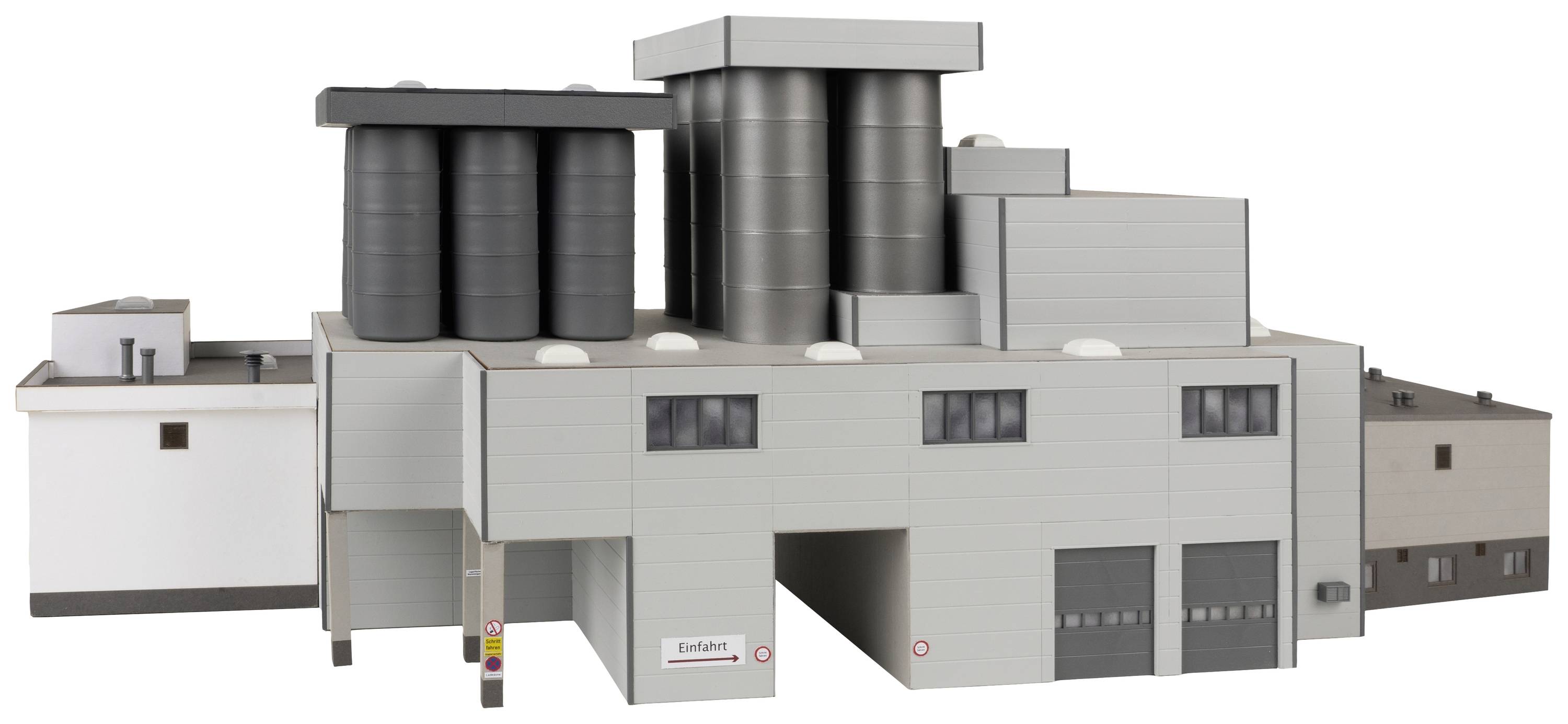 Budynek przemysłowy z wieloma dużymi zbiornikami i kominami na prostokątnej bryle; przedstawienie architektury przemysłowej.