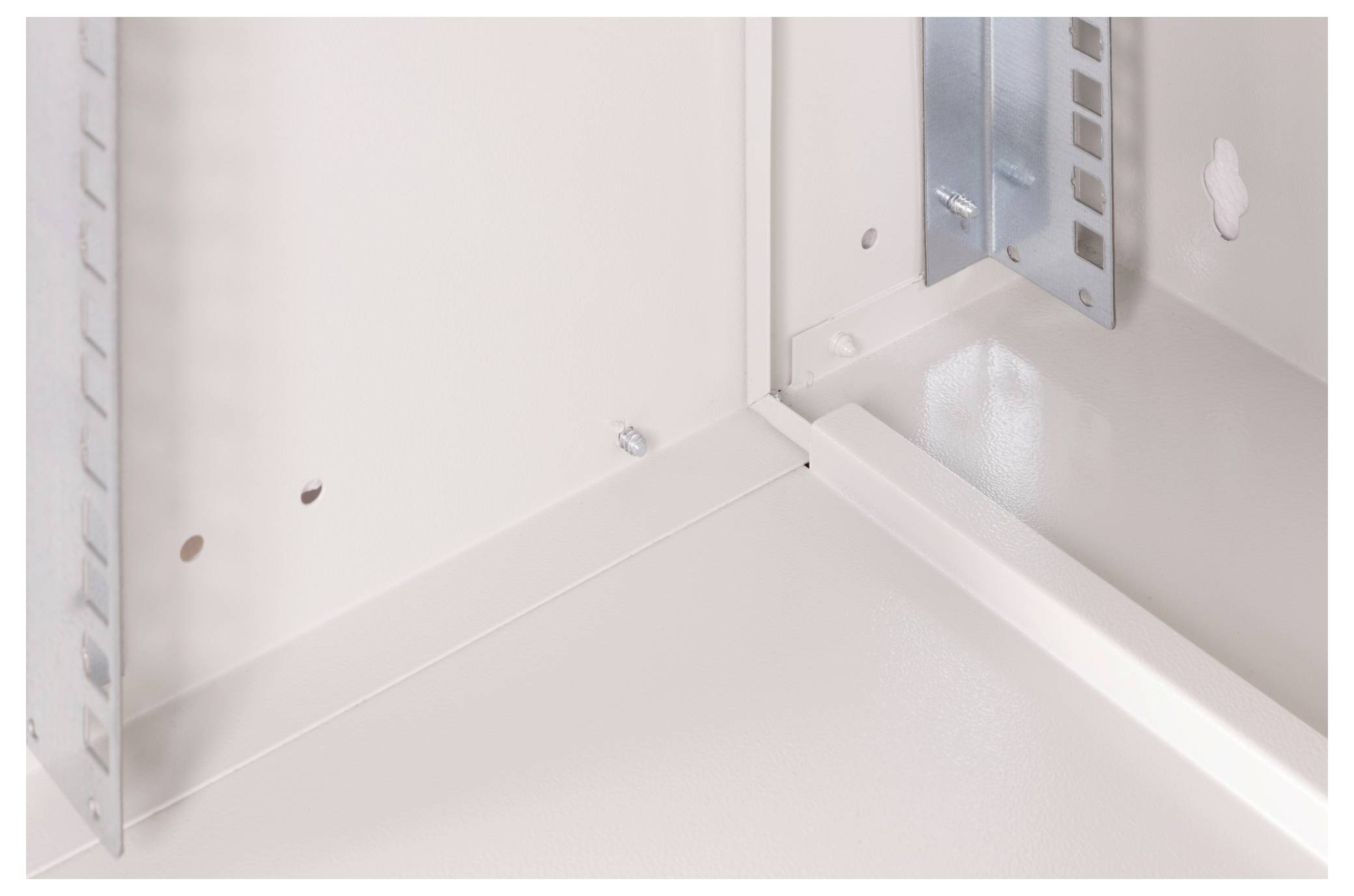 Beżowe wnętrze szafki technicznej z pionowymi i poziomymi szynami, widocznymi śrubami.