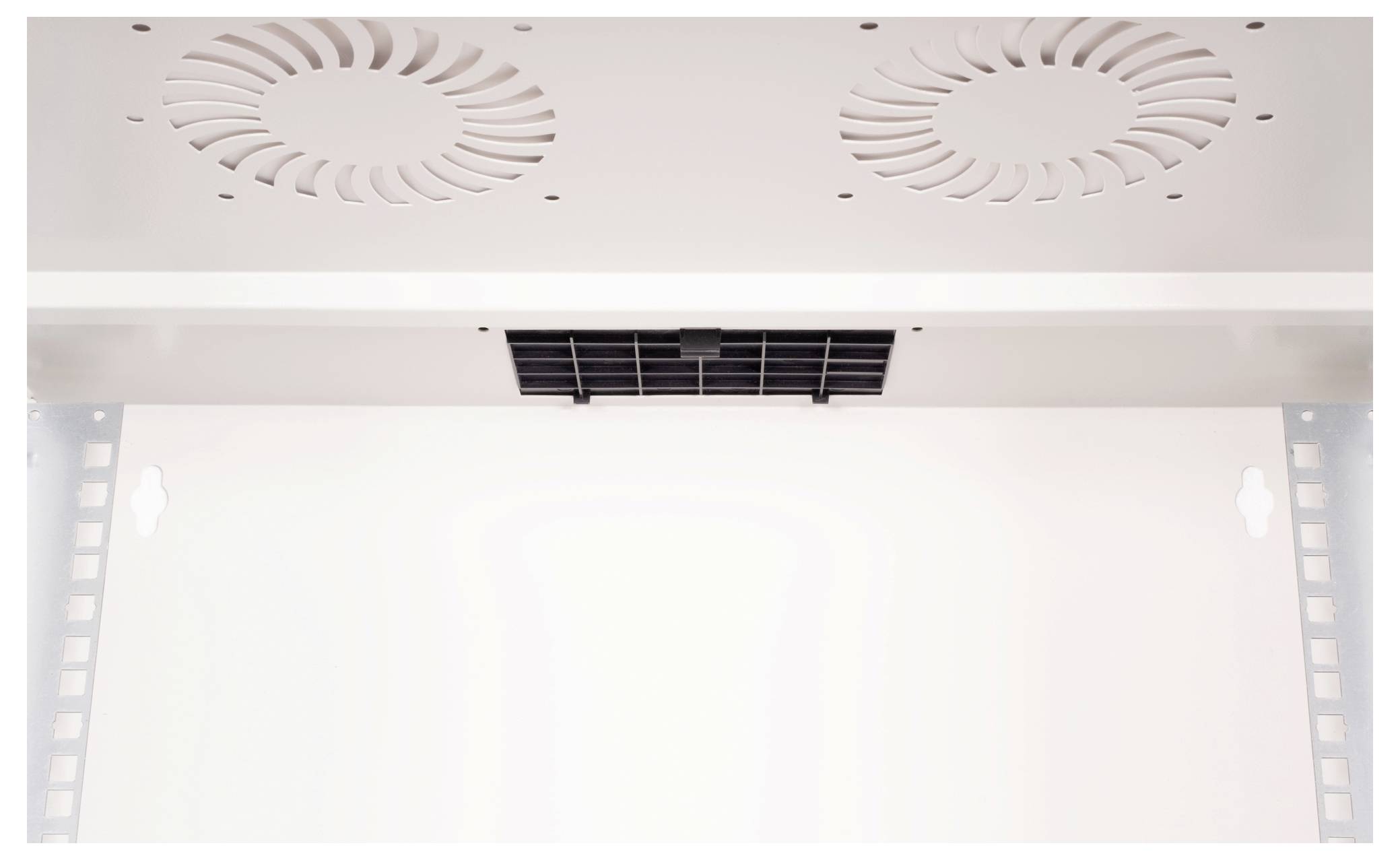 Obraz przedstawia widok wewnętrzny białego urządzenia chłodniczego z dwoma wentylatorami u góry oraz prostokątną kratką wentylacyjną pośrodku.