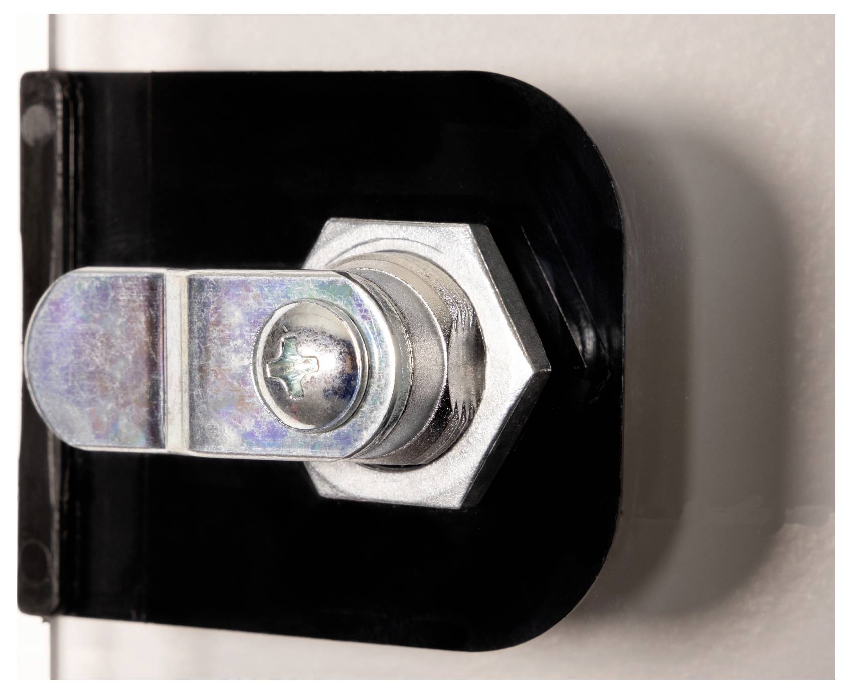 Mały metalowy zamek do drzwi z sześciokątną śrubą zamocowany na czarnym uchwycie, przymocowany z boku na białym tle.