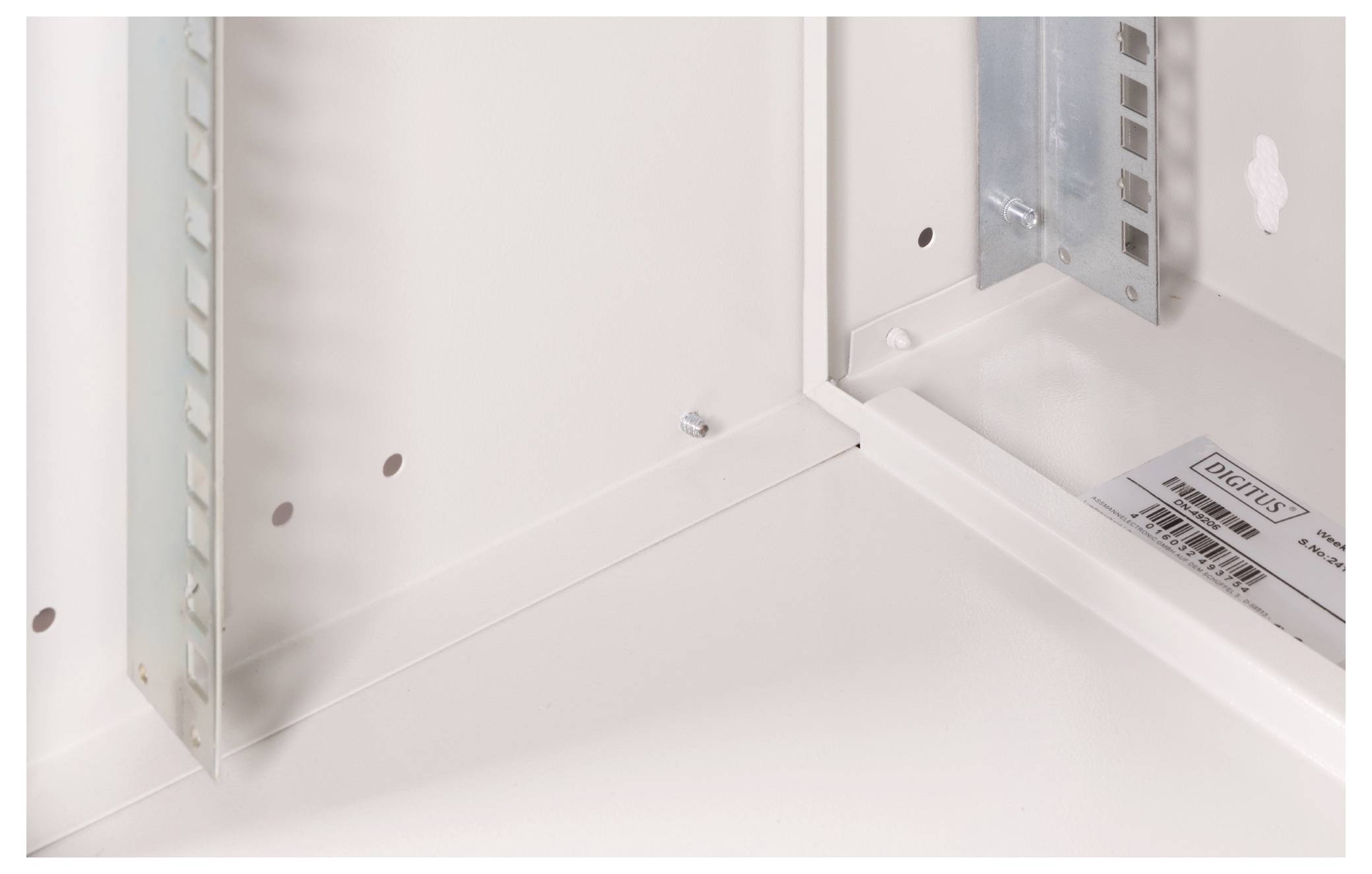 Puste, białe metalowe obudowanie z widocznymi otworami na śruby oraz dyskretną etykietą producenta w prawym dolnym rogu.