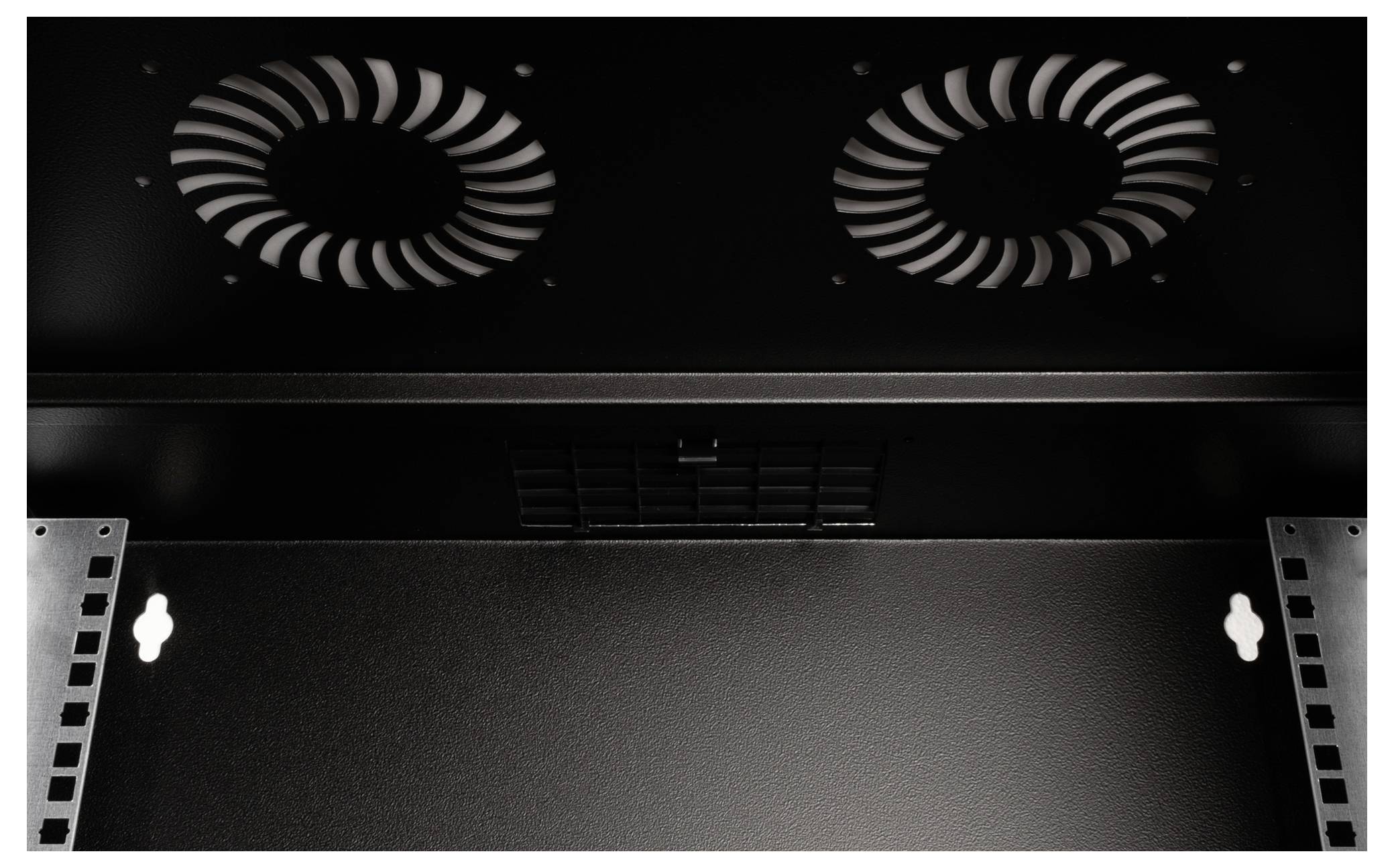 Widok wewnętrzny czarnej obudowy serwera z dwoma wentylatorami umieszczonymi na górze, służącymi do chłodzenia. Po lewej i prawej stronie znajdują się mocowania dla urządzeń.