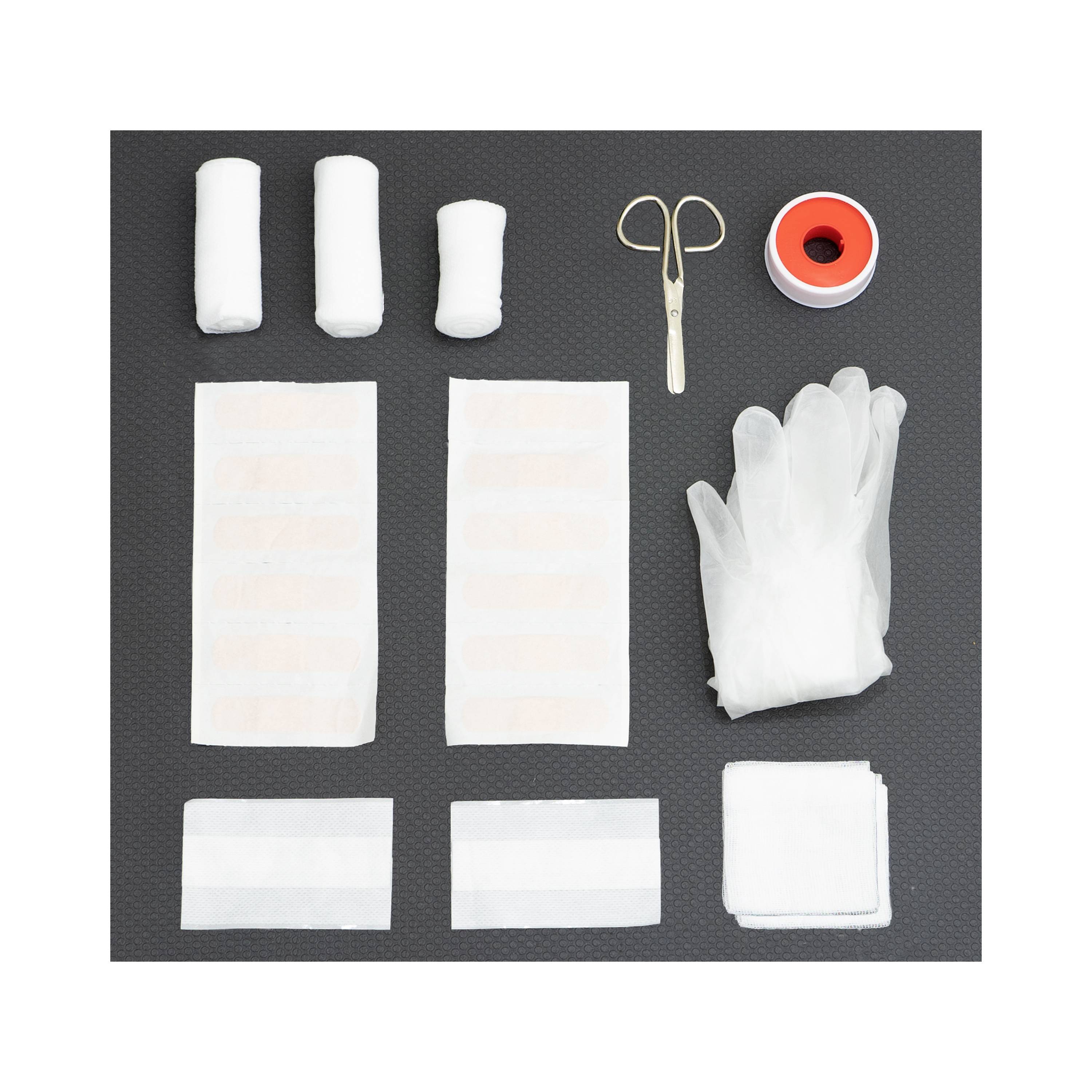 Zestaw pierwszej pomocy z bandażami, nożyczkami, taśmą klejącą, rękawiczkami i kompresami gazowymi na czarnym tle.