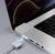 Laptop z podłączonym magnetycznym kablem ładującym, który świeci. Na ekranie wyświetlają się abstrakcyjne wzory i kolory.