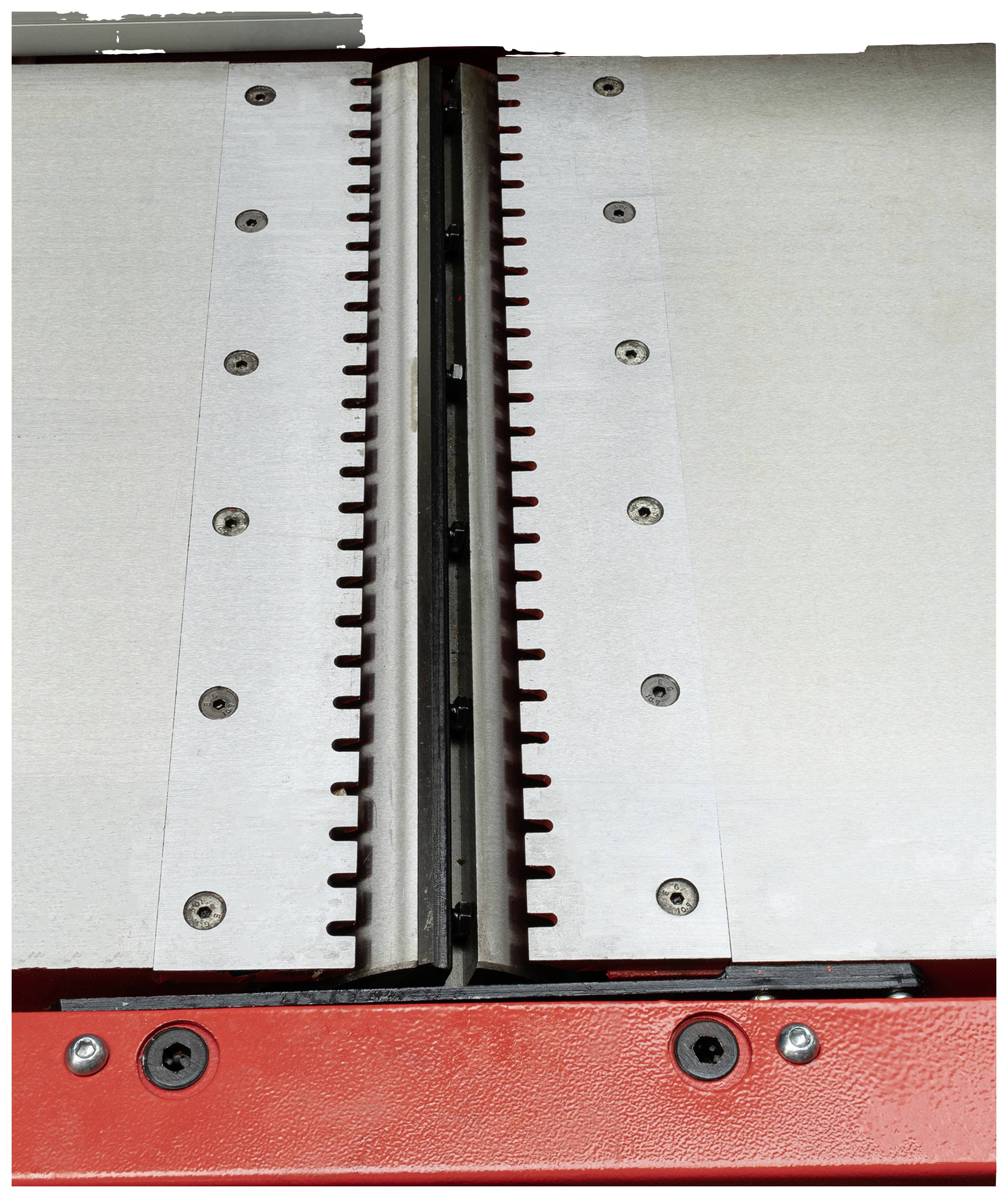 Maszyna z metalowymi ostrzami i śrubami, prawdopodobnie część narzędzia tnącego lub prasującego, na czerwonym podłożu.