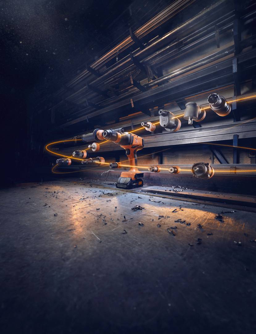 Obracający się akumulatorowy wkrętak na podłodze warsztatu, otoczony smugami światła, które przedstawiają ruch i dynamikę w przestrzeni przemysłowej.