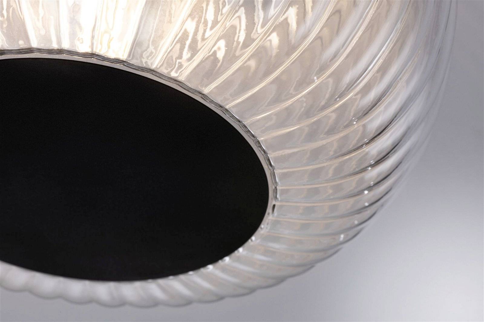 Zbliżenie nowoczesnej, przezroczystej lampy sufitowej o spiralnym wzorze z czarnym wnętrzem, rozpraszającej miękkie światło.