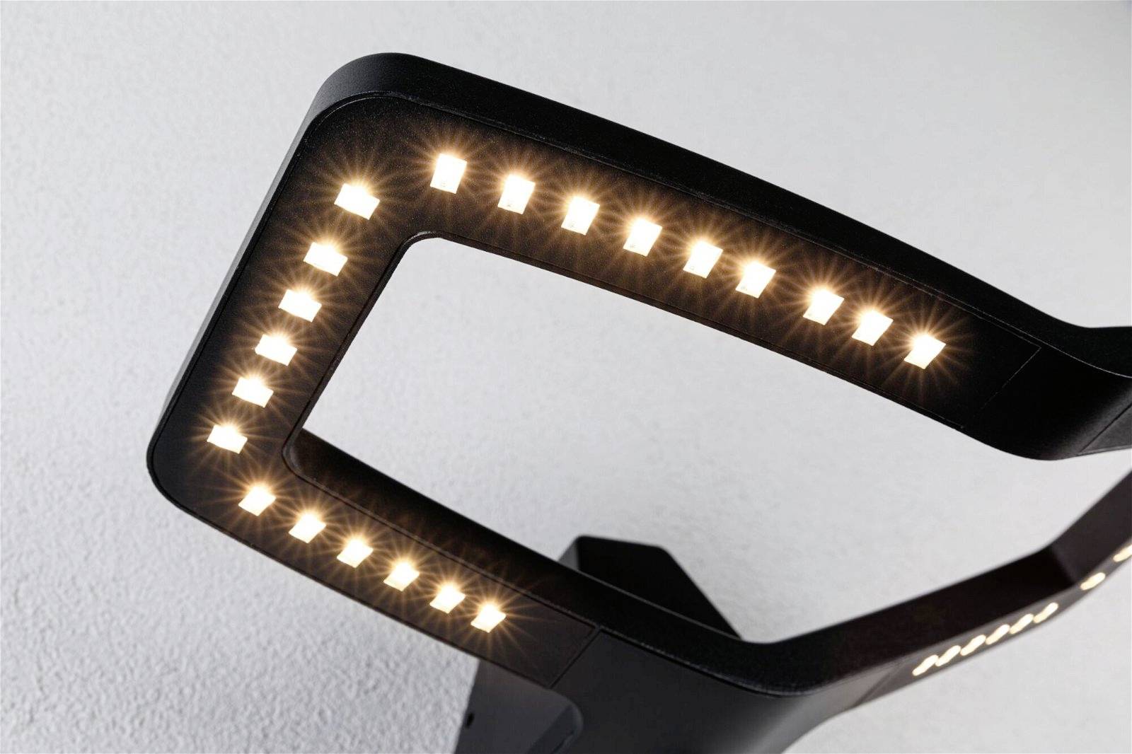 Nowoczesna lampa stojąca z prostokątną, świecącą ramą LED w minimalistycznym stylu, zamontowana przy białej ścianie.