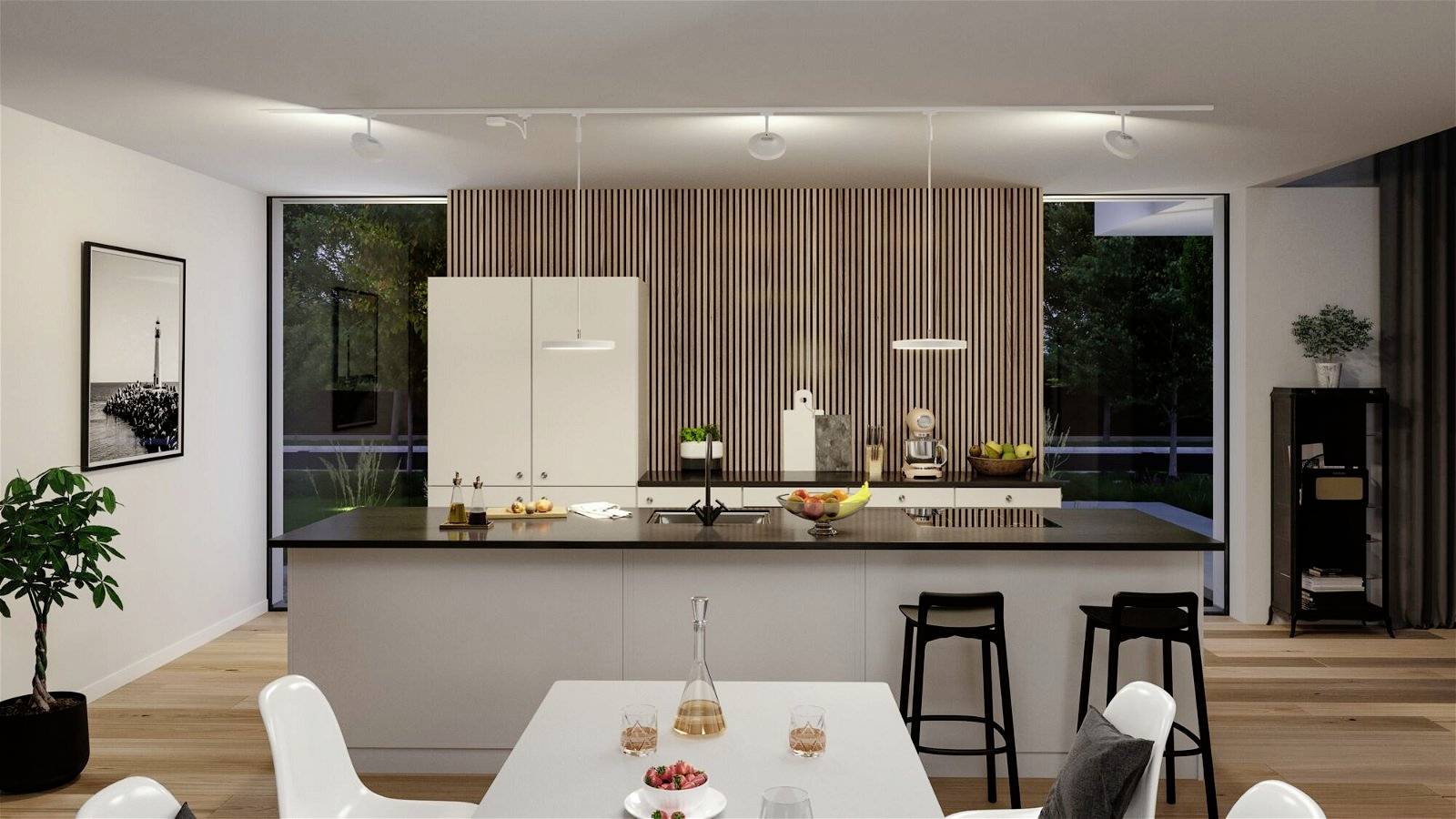 Nowoczesna kuchnia z dużą wyspą kuchenną, stołkami barowym i stołem jadalnianym. Jasne ściany, drewniane detale oraz okna w tle zapewniają dużo światła.