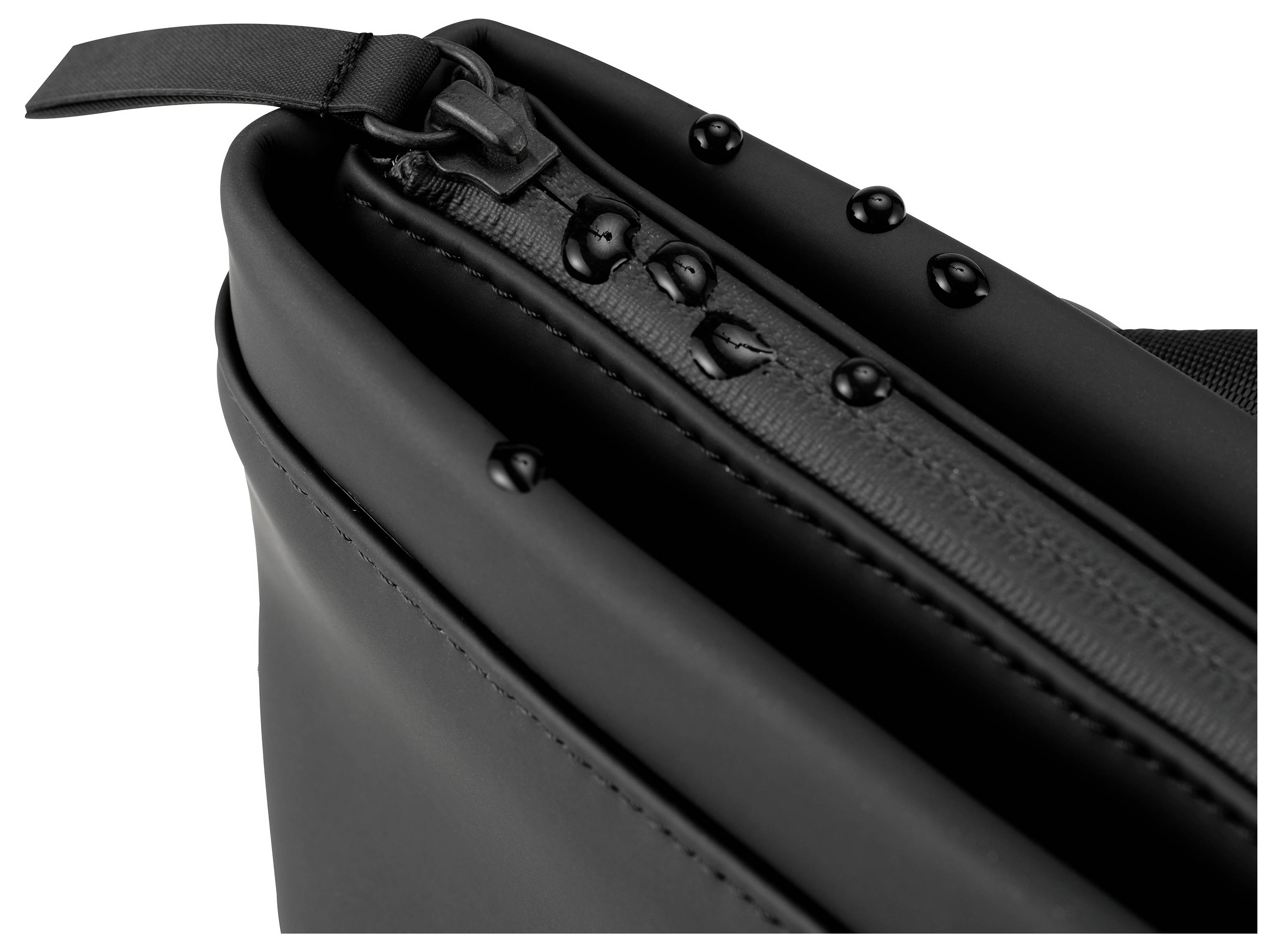 Zbliżenie czarnej torby z wodoodpornym zamkiem błyskawicznym, na którym leżą krople wody.