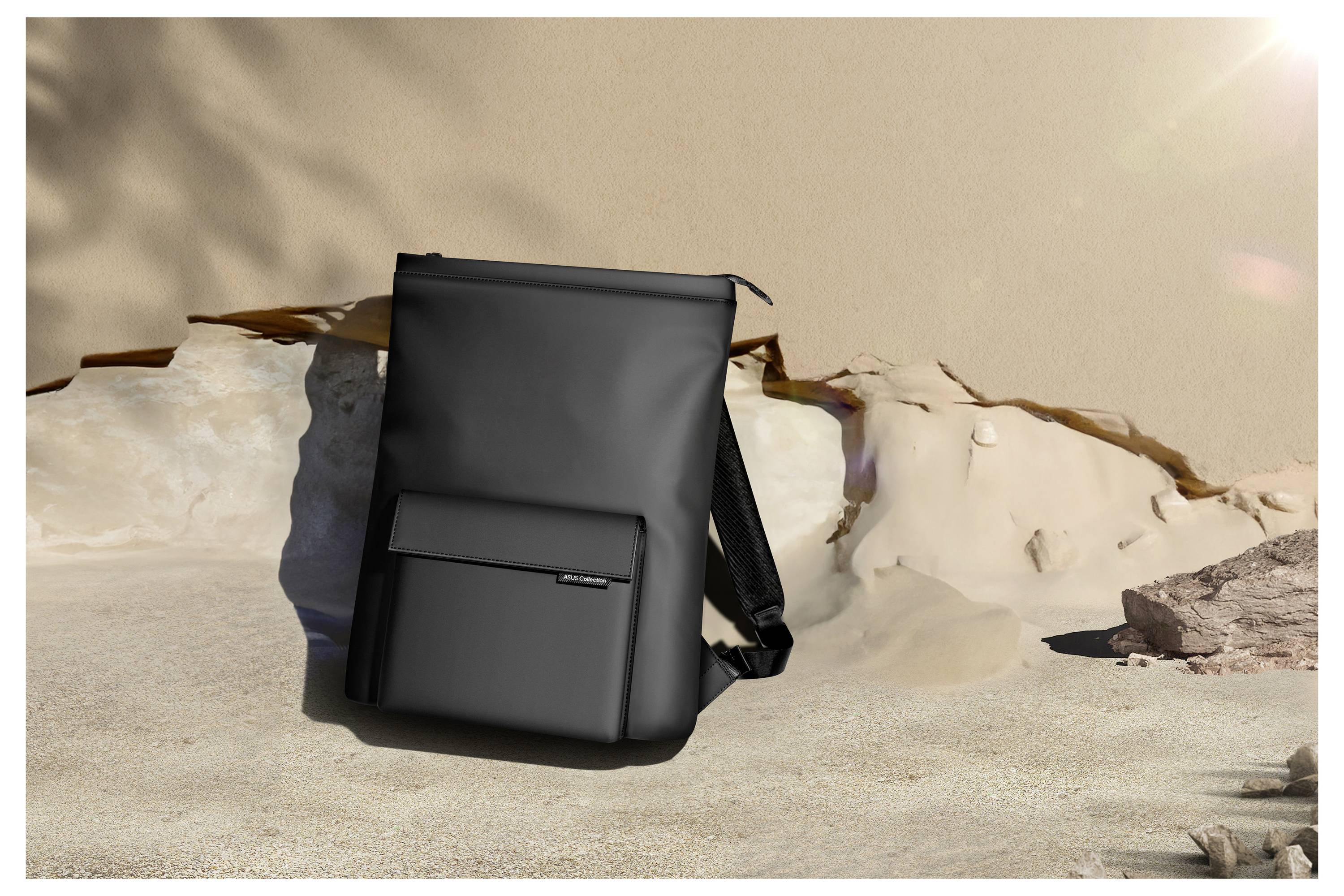 Czarny plecak stoi na piaszczystym gruncie przed skalistą ścianą. Cienie i gra świateł tworzą spokojną atmosferę.