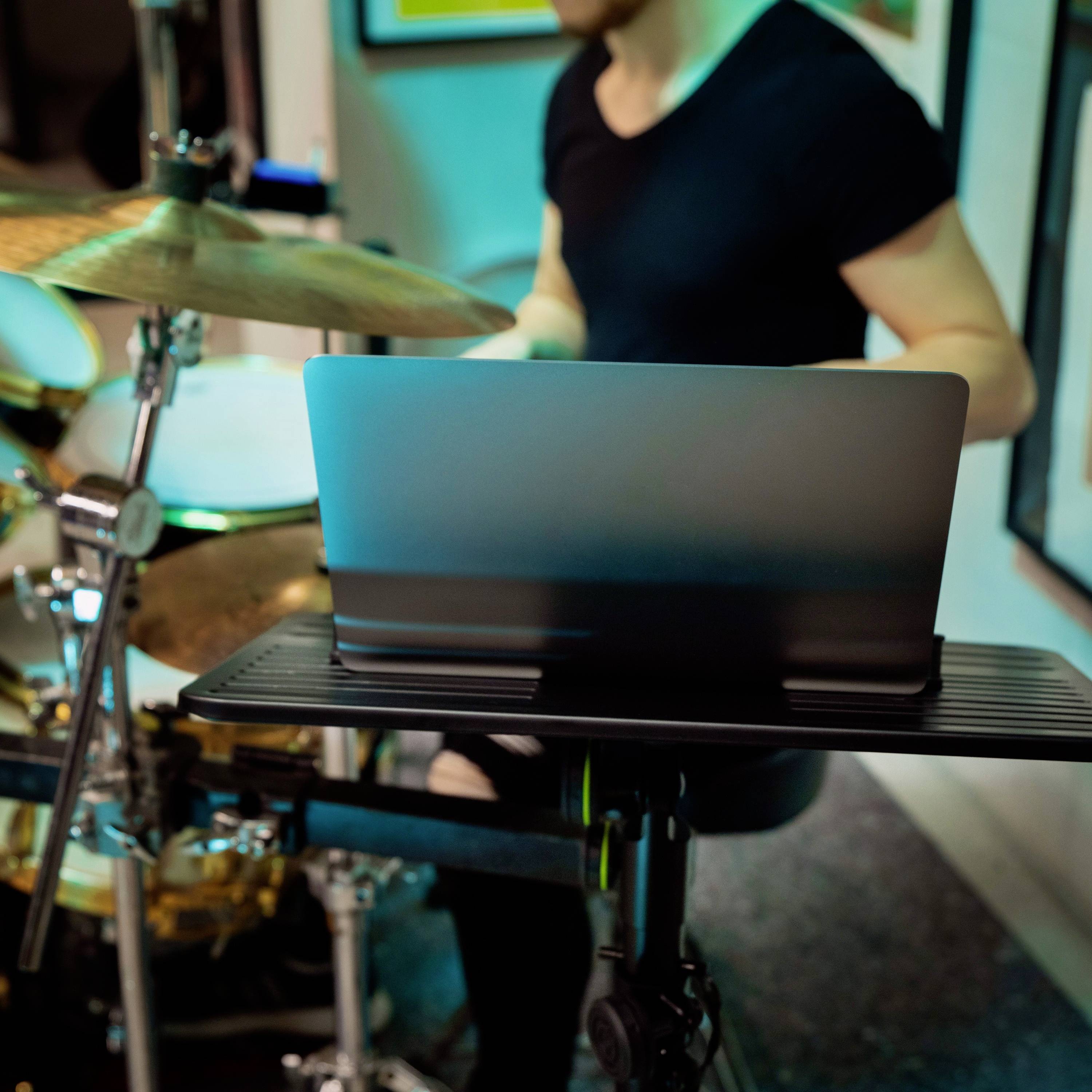 Osoba gra na perkusji obok laptopa.