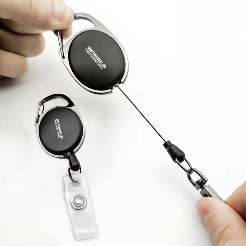 Ręka prezentuje wysuwany brelok z klipsem, przymocowany do karty lub dowodu osobistego.