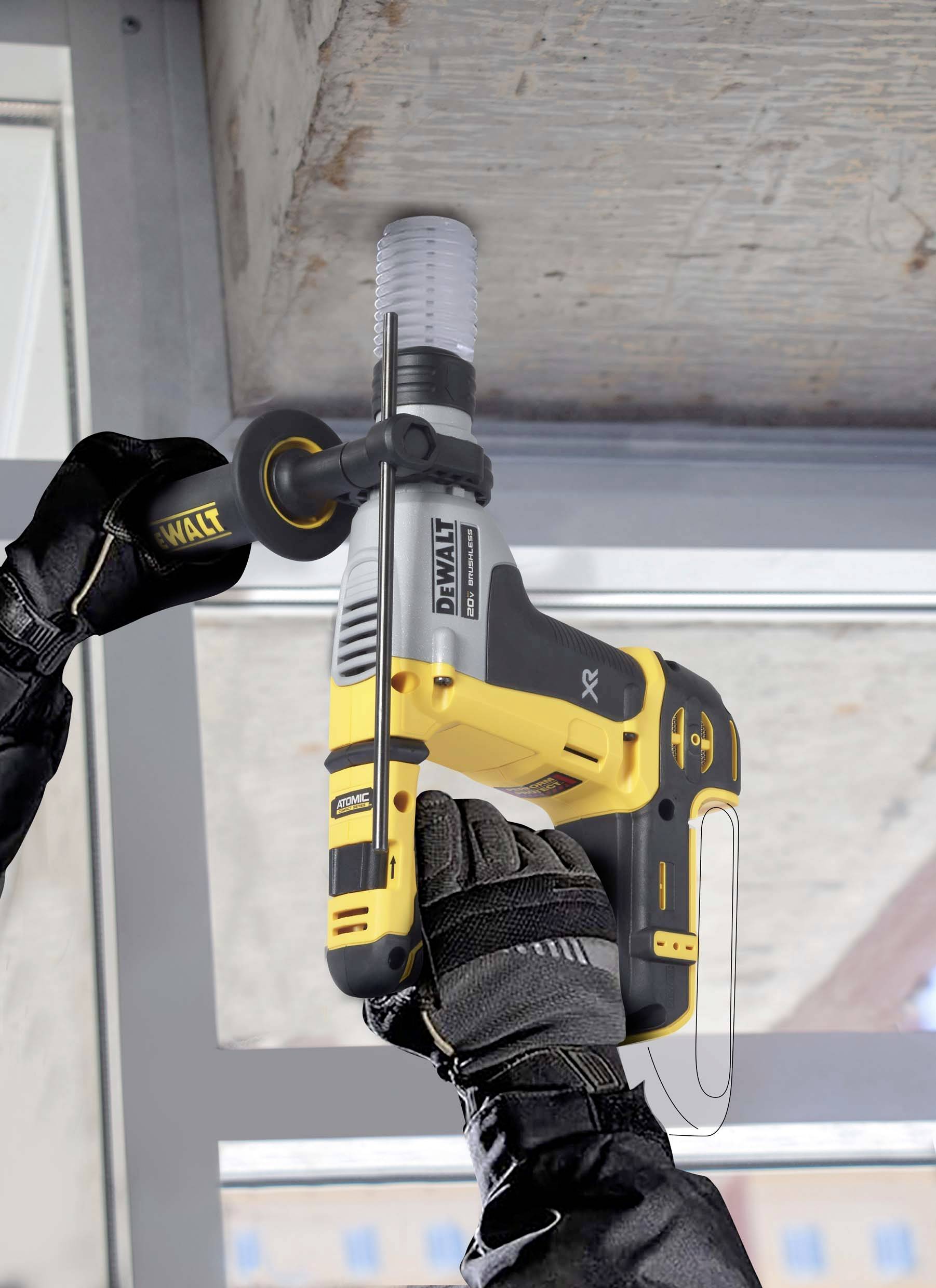 Osoba wierca żółtym elektronicznym narzędziem w blok betonowy. Osoba ma na sobie czarne rękawice.