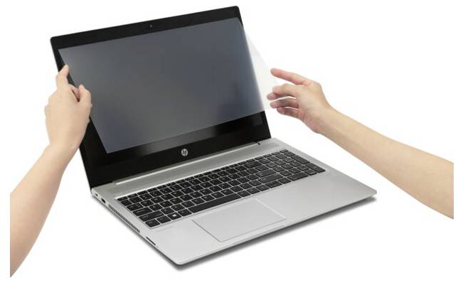 Laptop z otwartym ekranem. Dwie ręce trzymają ochronną folię przed wyświetlaczem, aby ją zamocować lub dopasować.