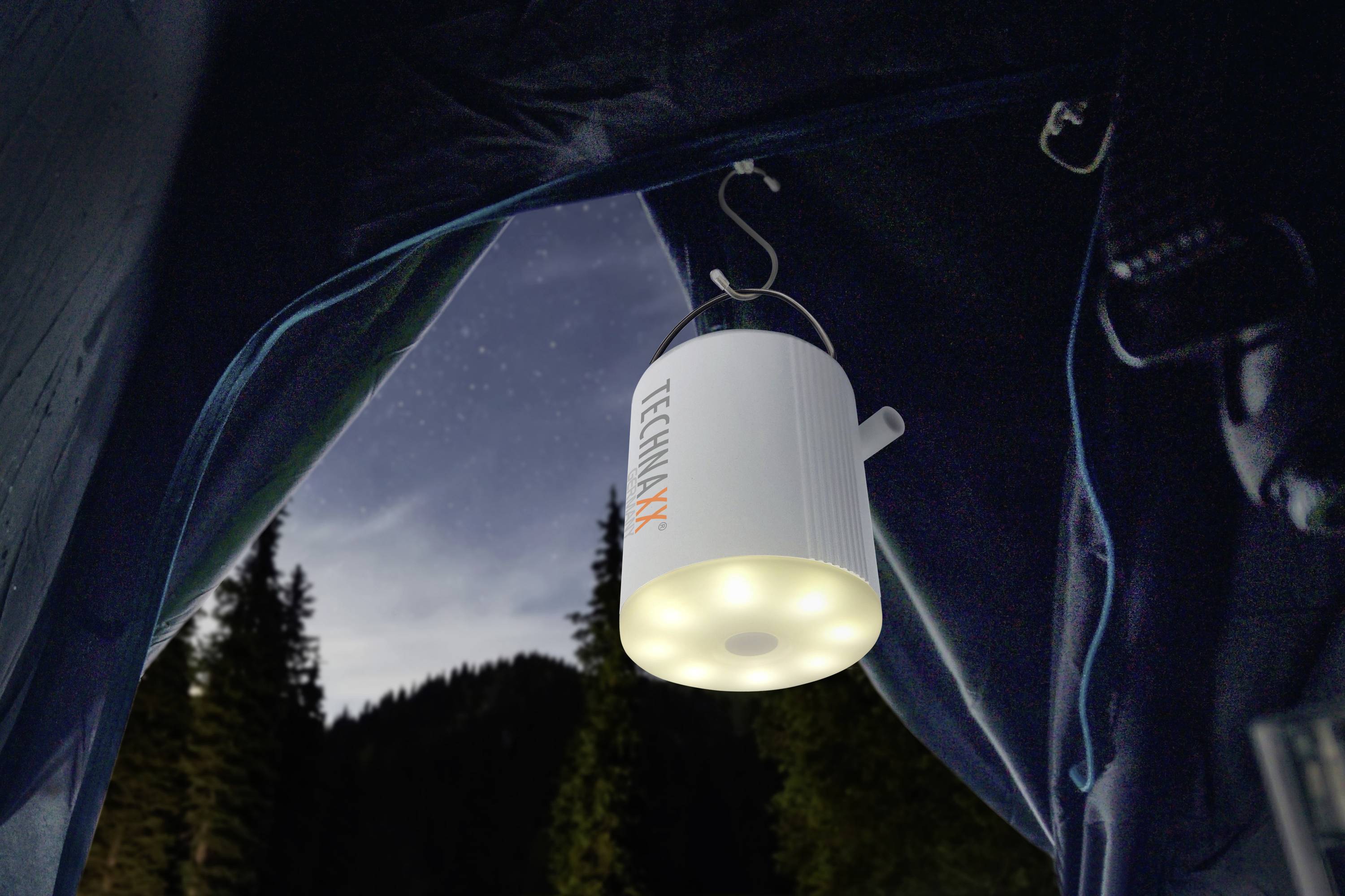 Namiot z wbudowaną lampą LED, która świeci w ciemności. Niebo jest gwiaździste, z zarysami drzew w tle.