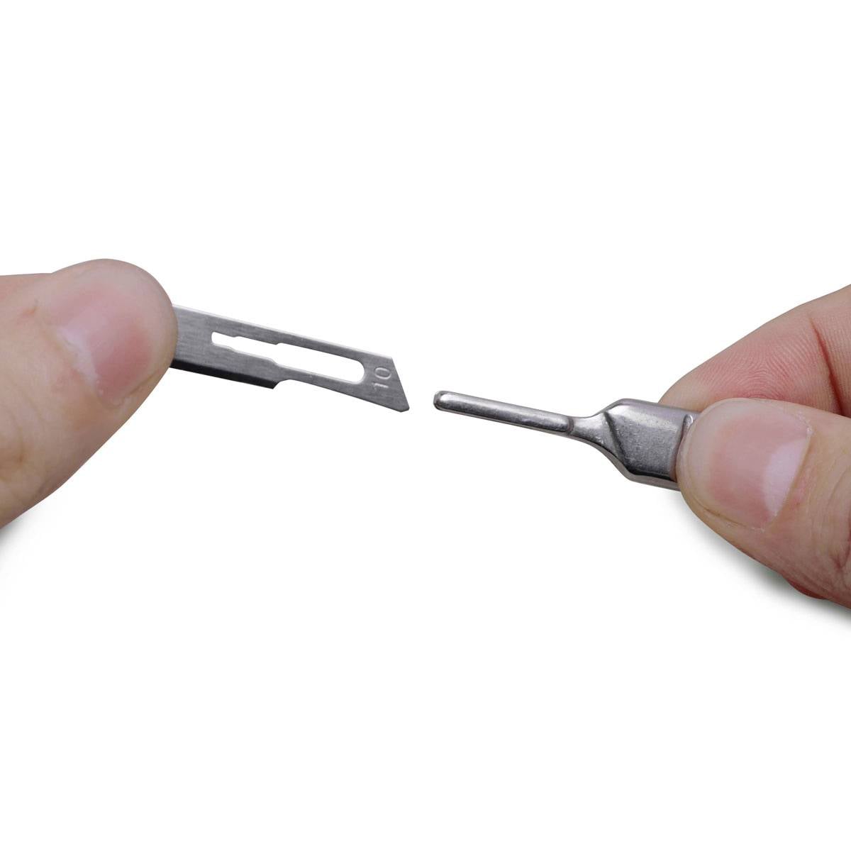 Dwie ręce trzymają uchwyt ostrza skalpela i ostrze przygotowane do zamontowania.