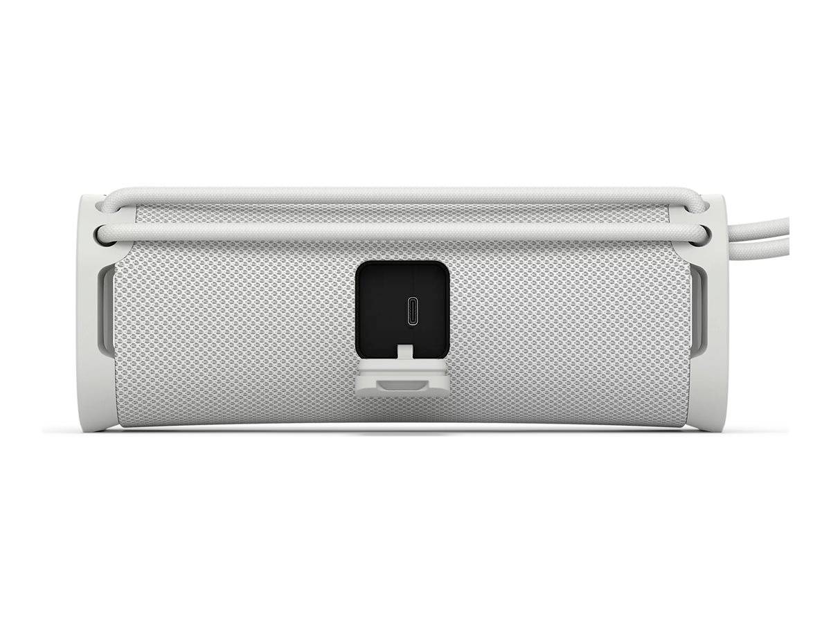 Przenośny głośnik w białym kolorze z otworem na złącze ładowania pośrodku.