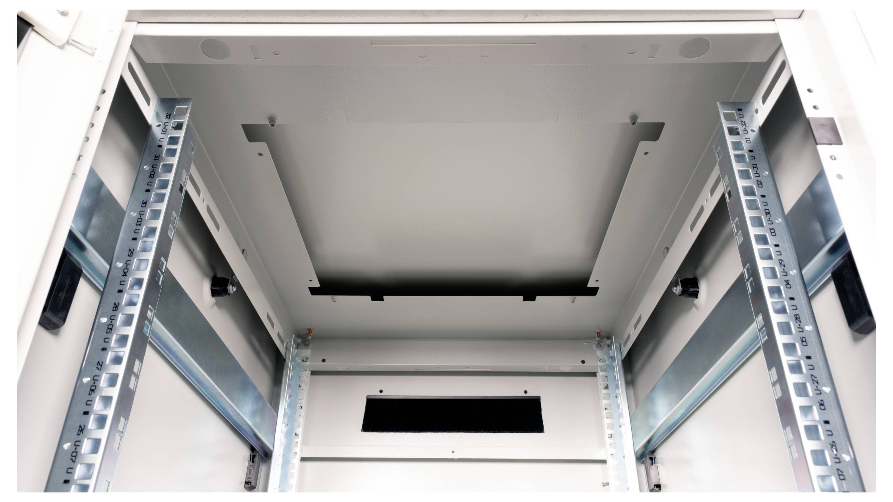 Pusty, otwarty szafa serwerowa widziany od wewnątrz, ukazuje metalowe stelaże i mocowania po bokach.