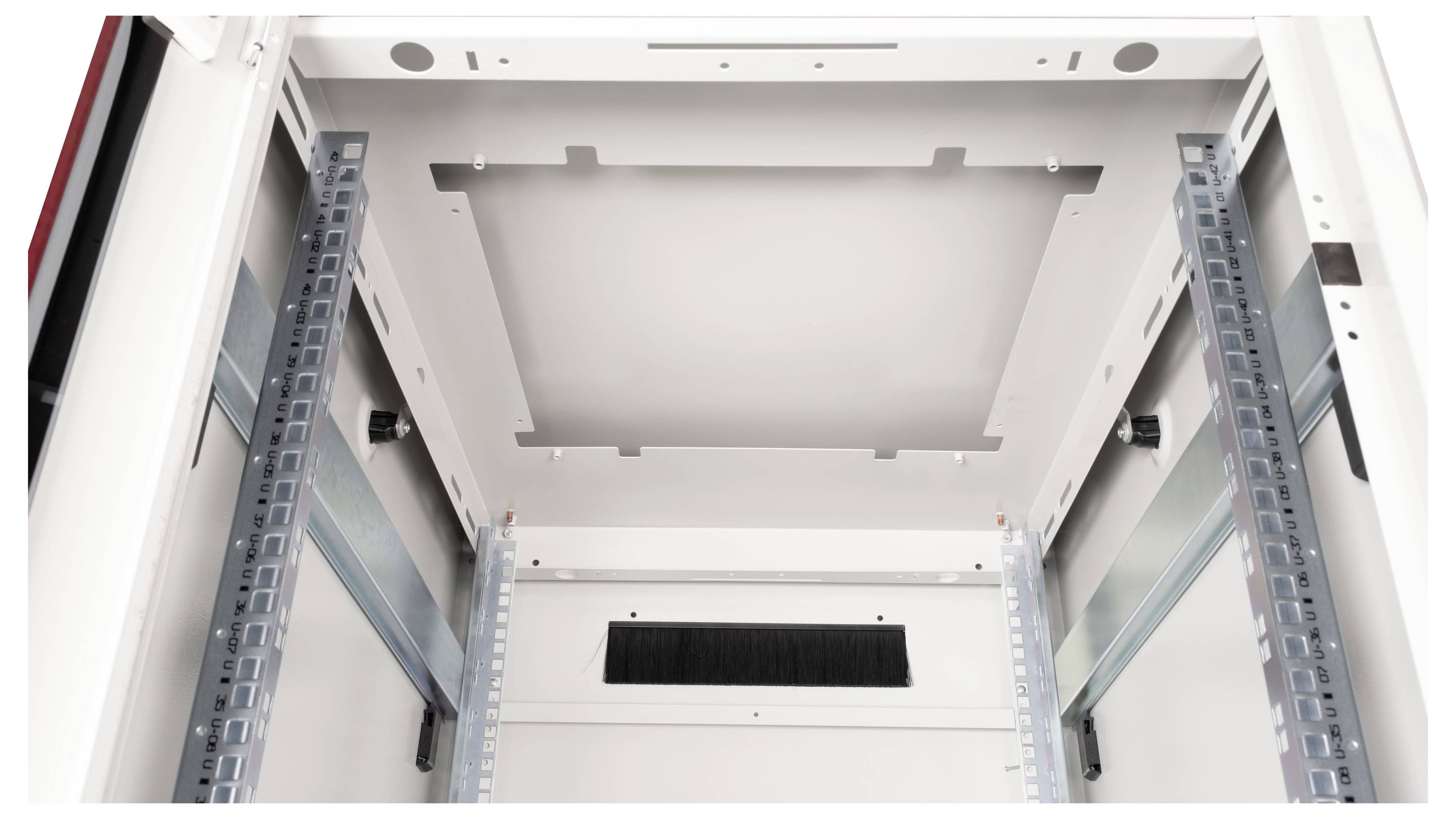 Widok wewnętrzny pustej szafy serwerowej z widocznymi szynami i elementami mocującymi, gotowy do instalacji urządzeń.