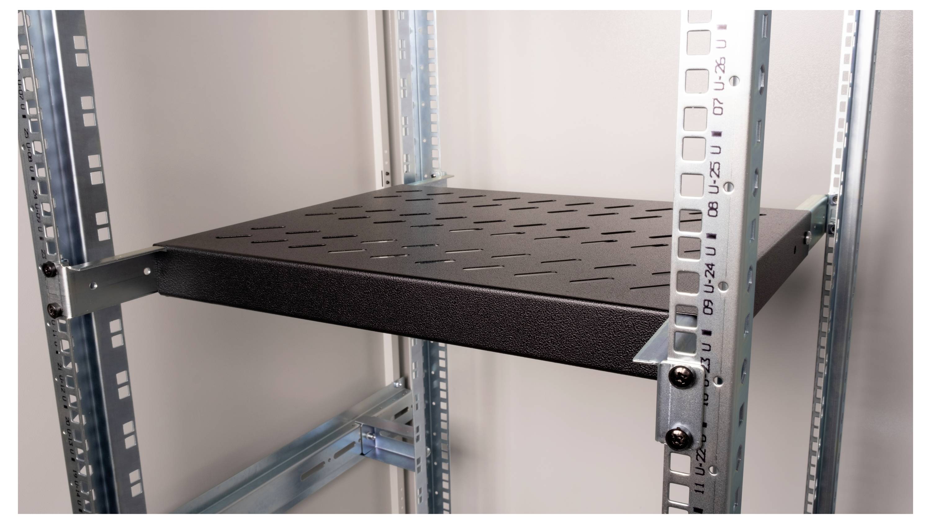 Regał metalowy z czarną kratową półką, zamontowany w otwartej ramie nośnej.