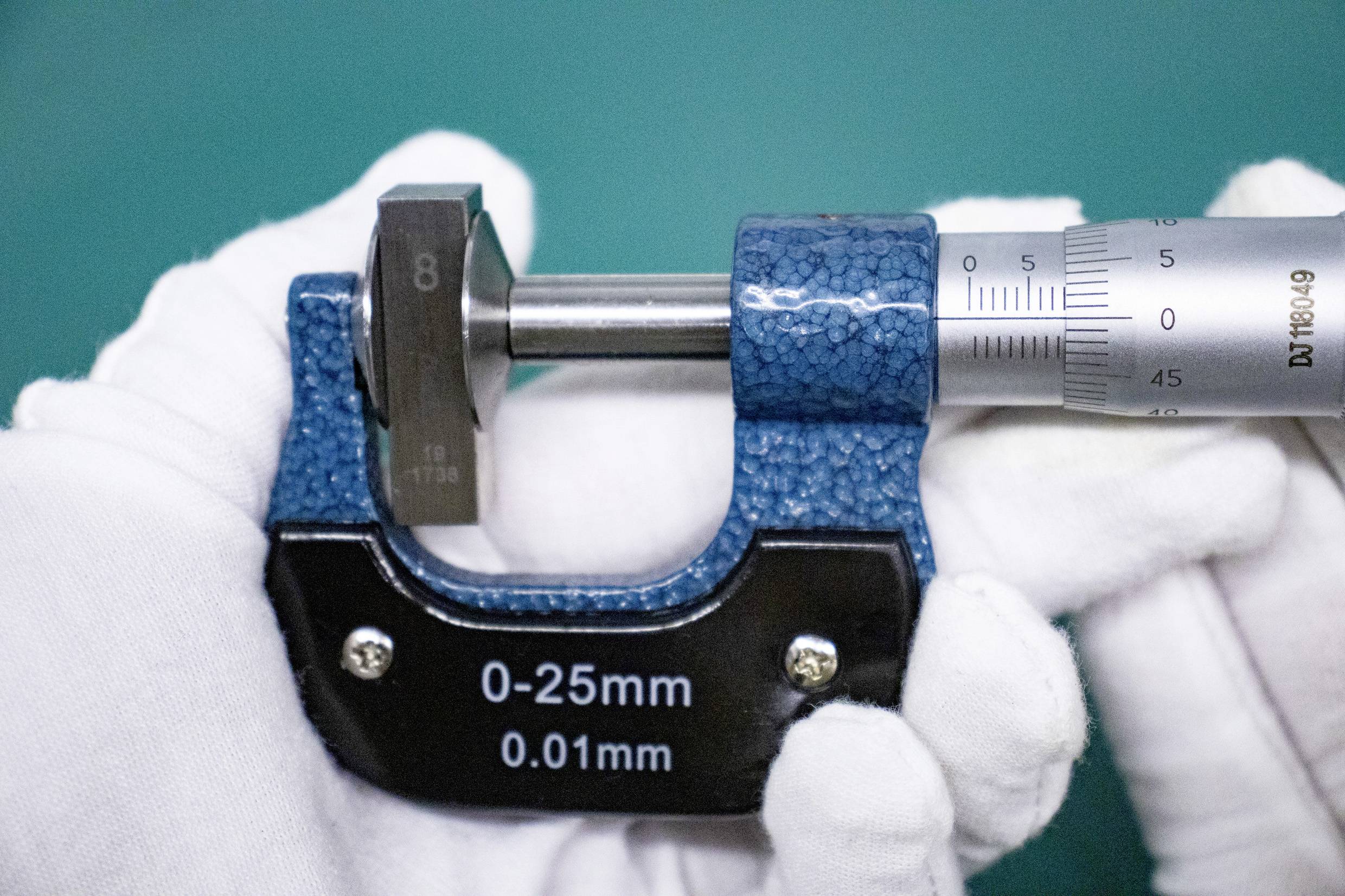 Śruba pomiarowa mierzy blok metalowy. Skala wskazuje wartość pomiędzy 14 a 15 mm. Oznaczenie bloku: '8'. Dokładność pomiaru: '0,01 mm'.