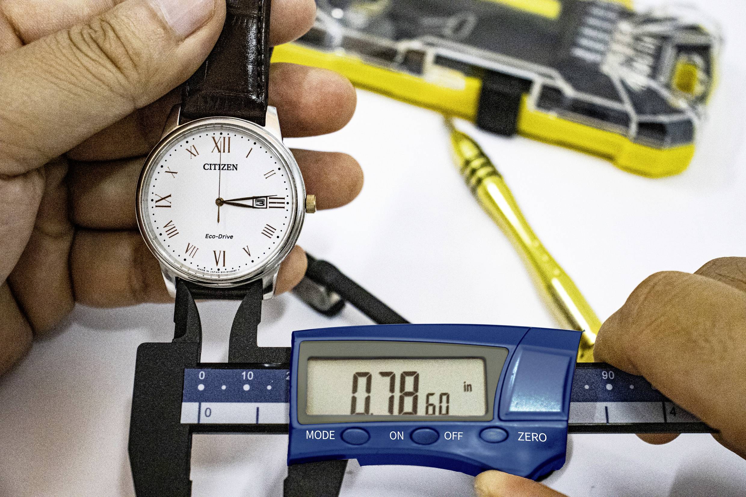 Mężczyzna mierzy średnicę zegarka za pomocą elektronicznego suwmiarki. Wyświetlacz pokazuje 0,7860 cala.