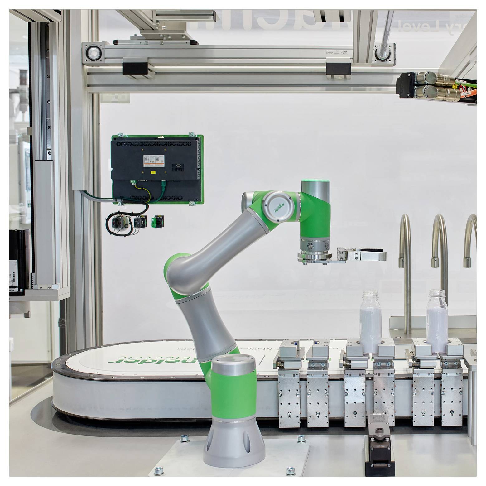 Przemysłowy ramię robota w laboratorium lub komórce produkcyjnej obok przenośnika, ustawione do obsługi małych butelek lub pojemników.