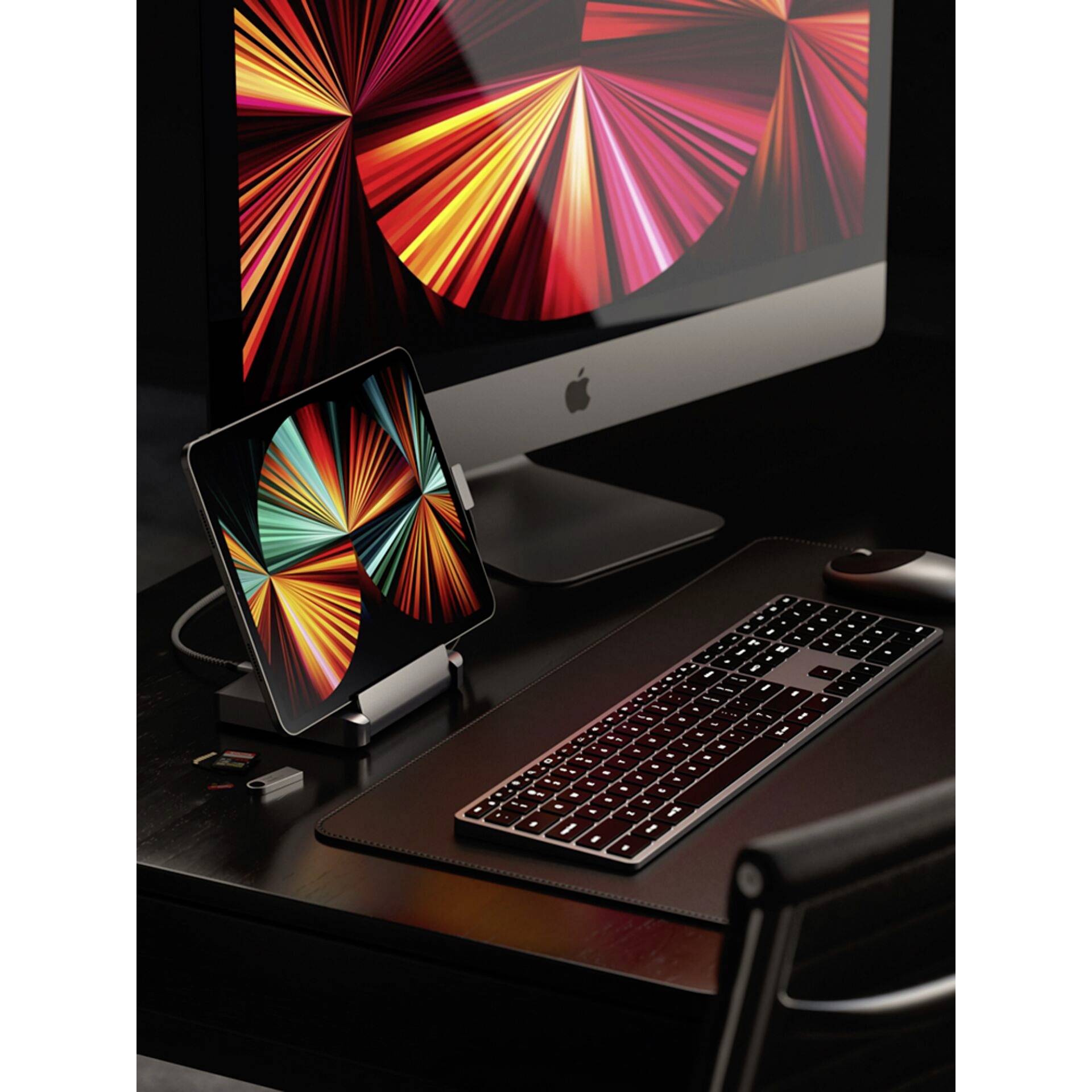 Biurko z komputerem i tabletem wyświetlającym tę samą kolorową grafikę. Obok leży klawiatura.