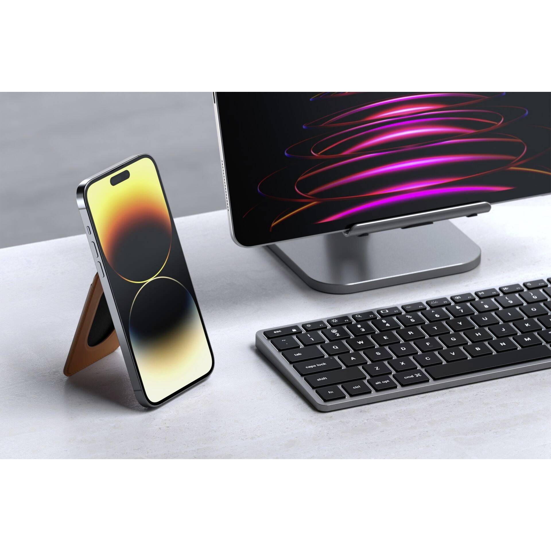 Smartfon stoi na stojaku obok klawiatury i ekranu wyświetlającego świecące, faliste wzory.