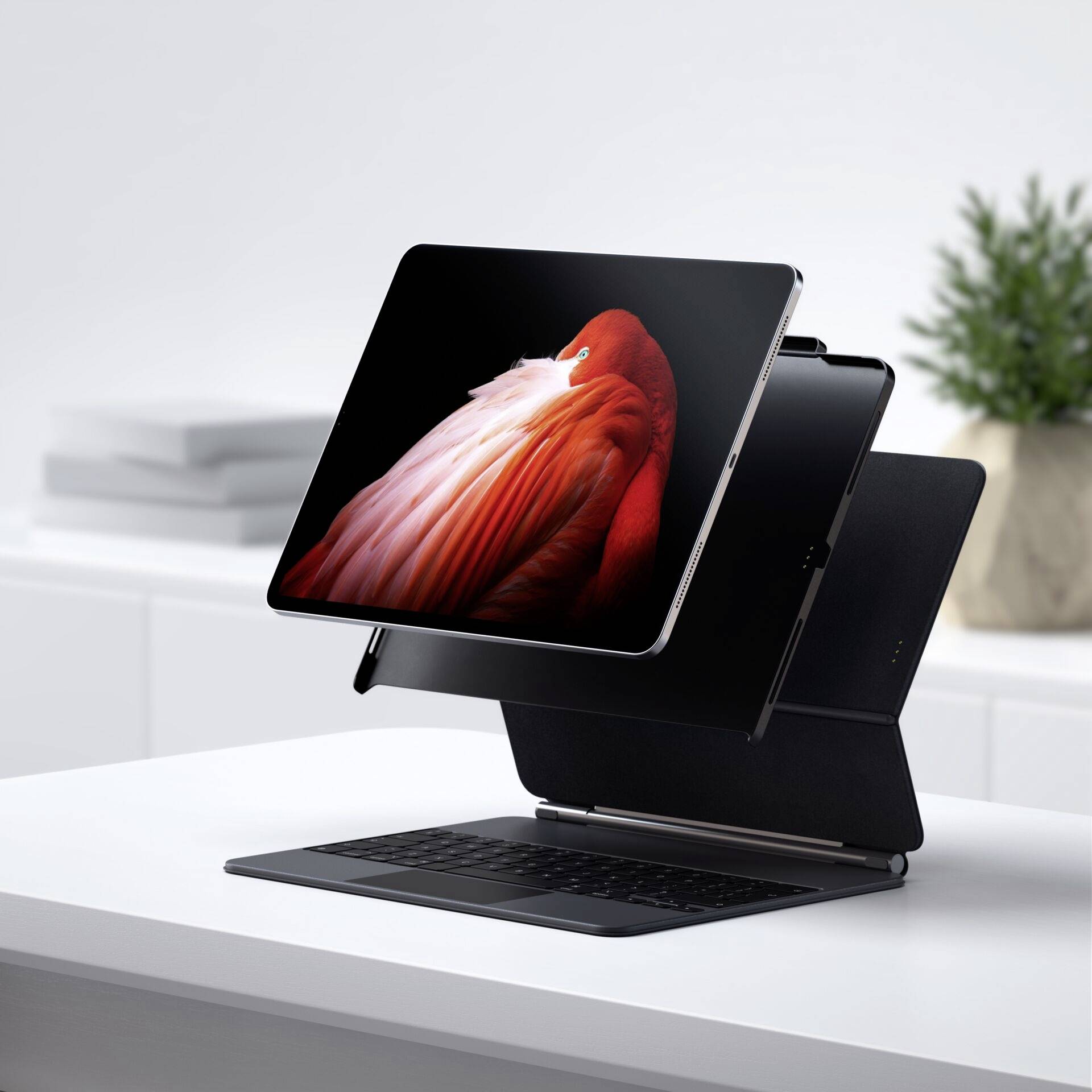 Tablet na składanym stojaku z klawiaturą, na białym biurku; rozmyty tło ze stosem dokumentów.