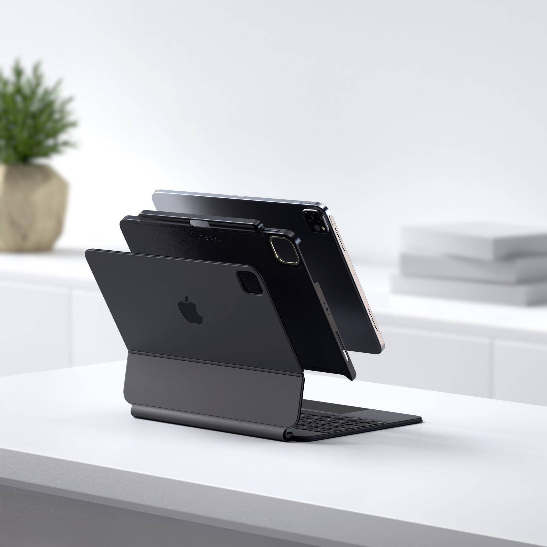 Tablet z etui z klawiaturą stoi na stole. W tle widoczny jest doniczka i nieostre urządzenia biurowe.