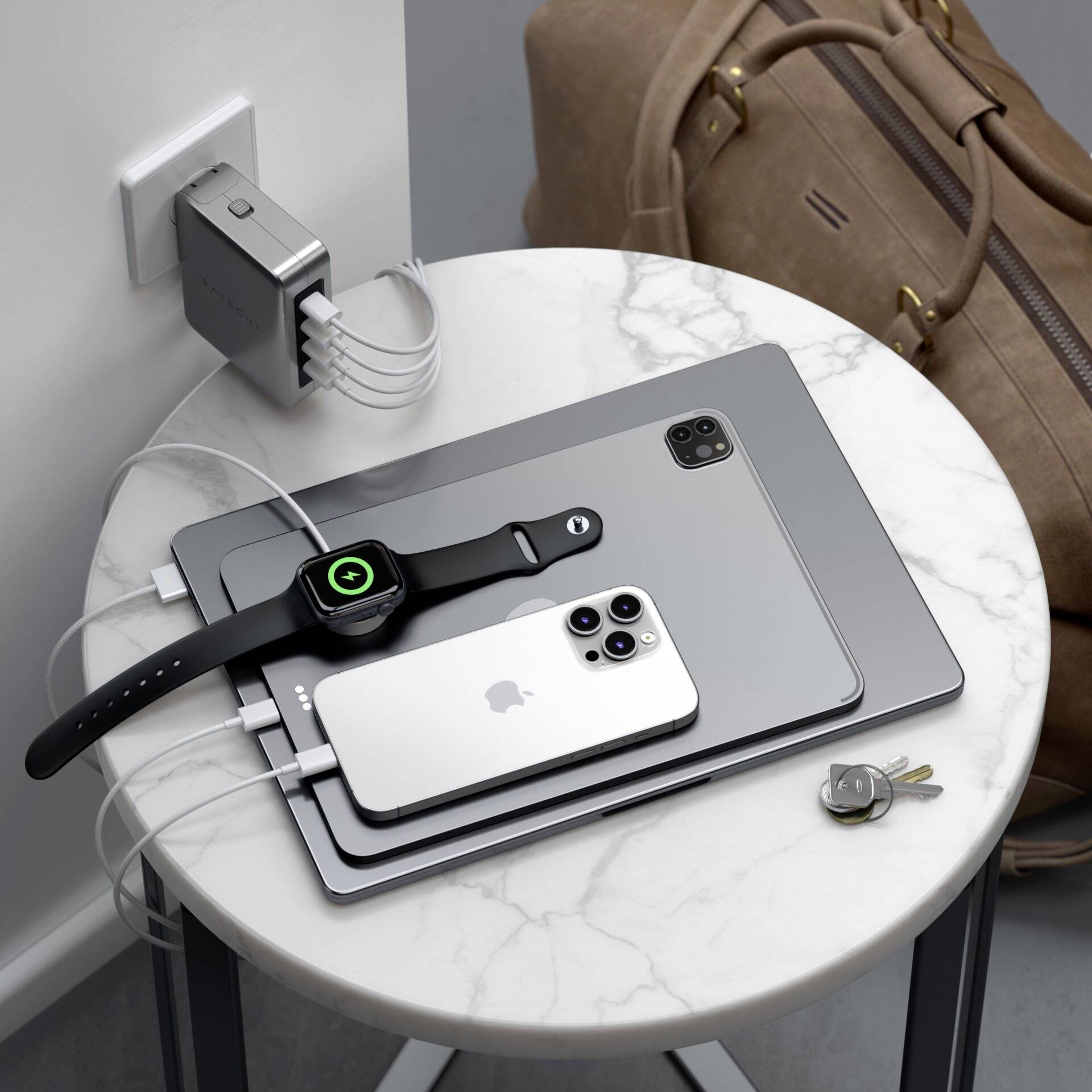 Na marmurowym stole leżą laptop, tablet, smartfon i zegarek, wszystkie podłączone do wspólnej ładowarki.