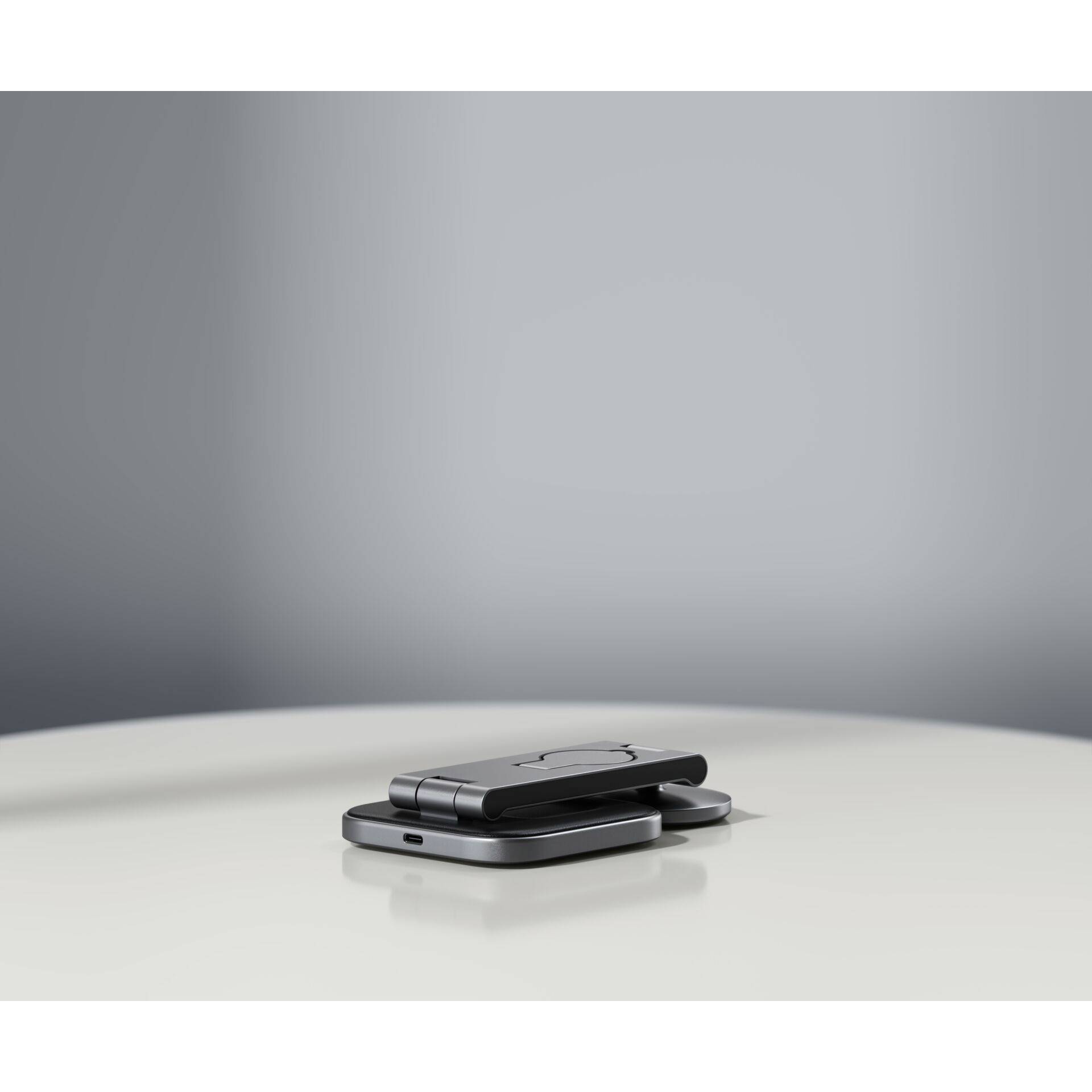 Złożony, nowoczesny telefon składany leży na stole na minimalistycznym, szarym tle.