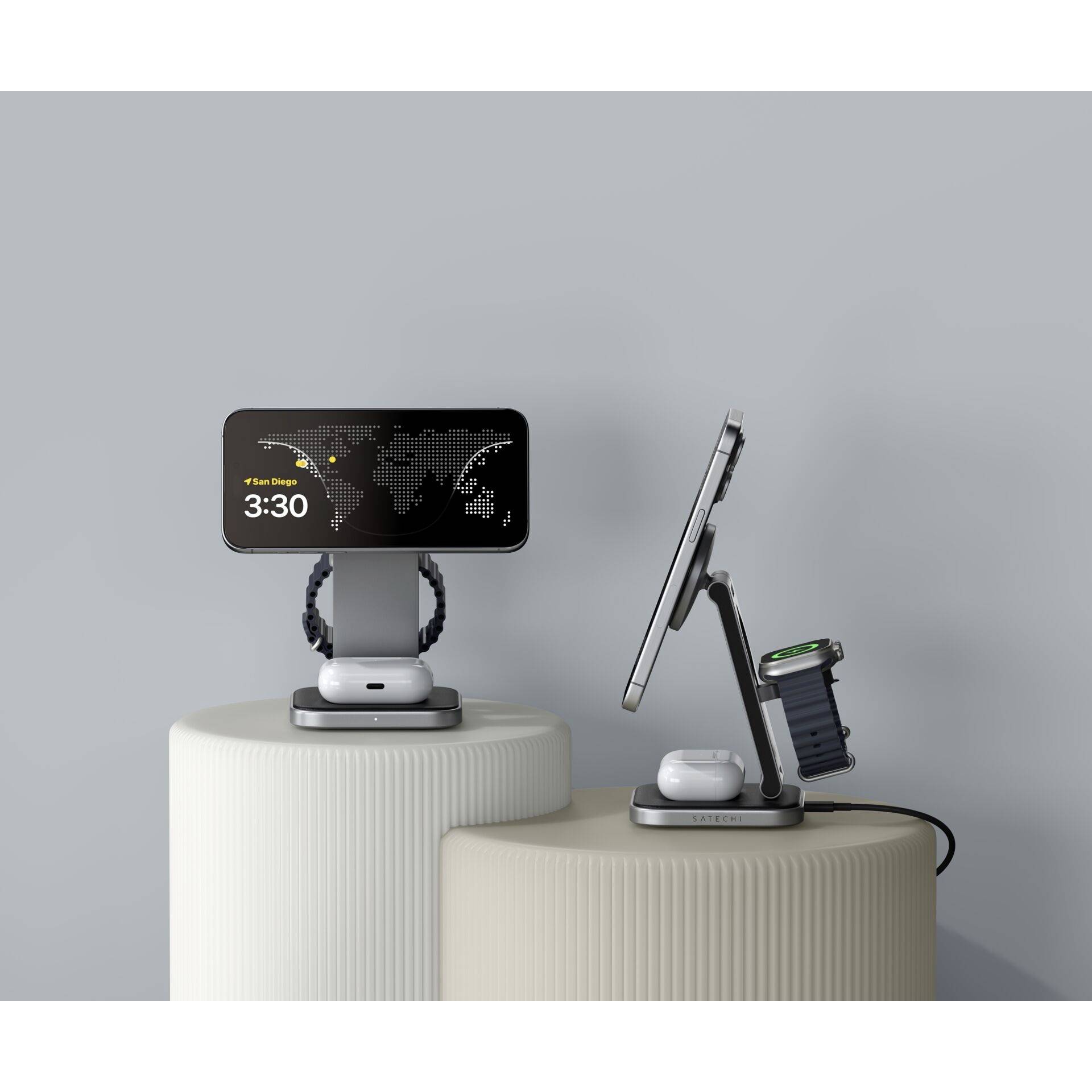 Smartfon i zegarek na stacjach ładujących, oba pokazujące godzinę '3:30'. Kabel łączy stację z źródłem energii.